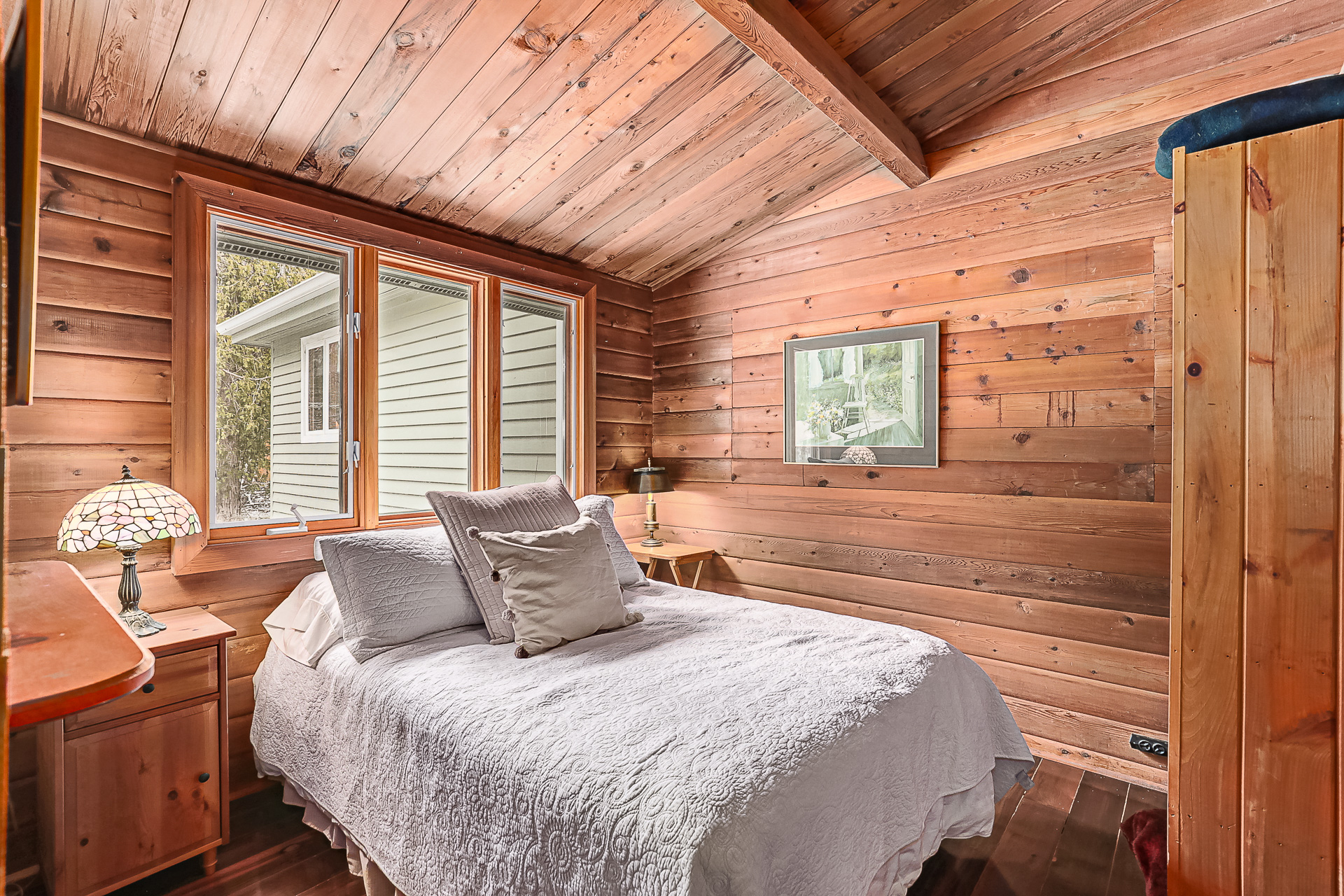 A white bed in a wood-paneled room