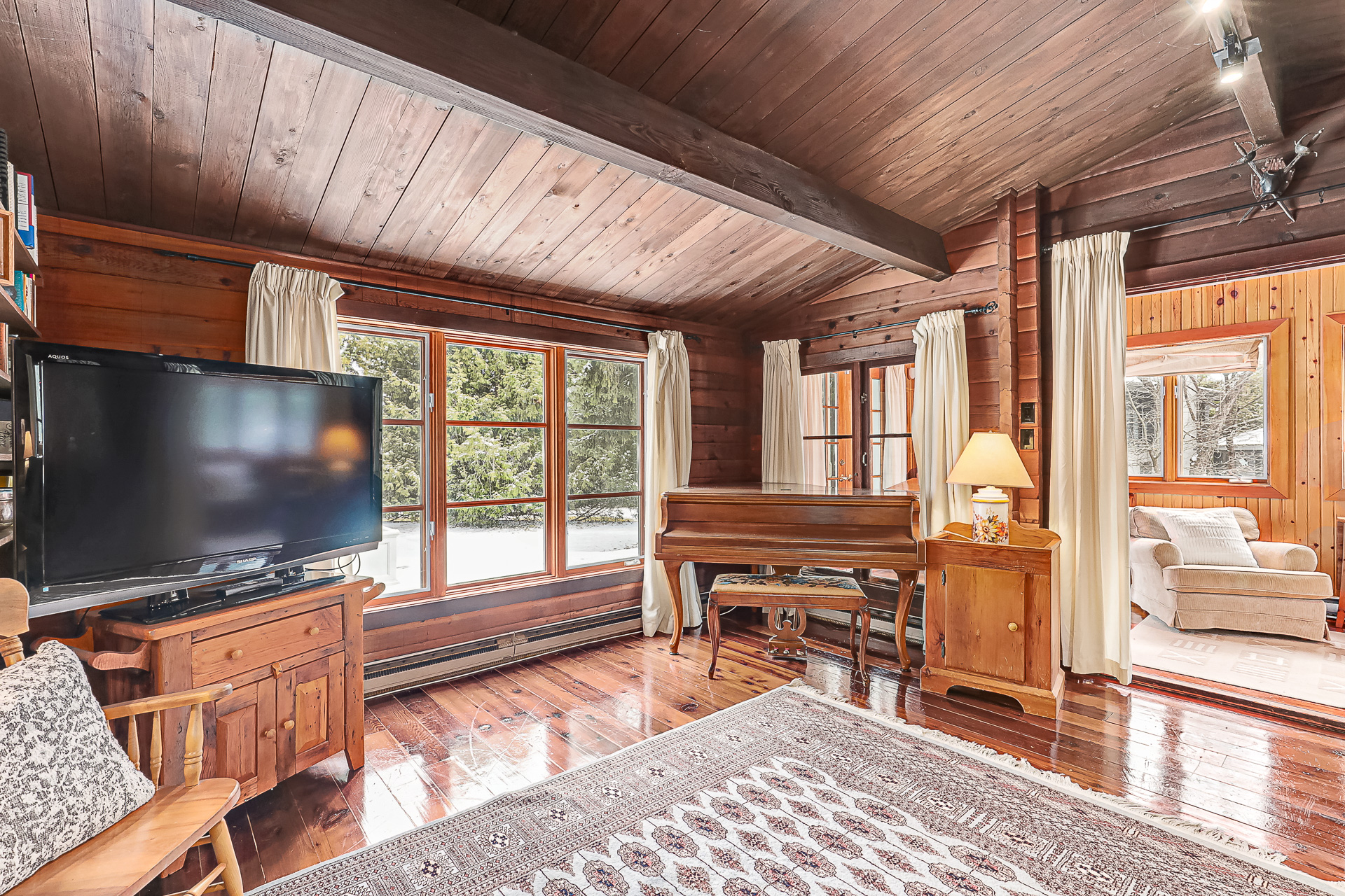 A TV on a wood stand in a bright wood-paneled room