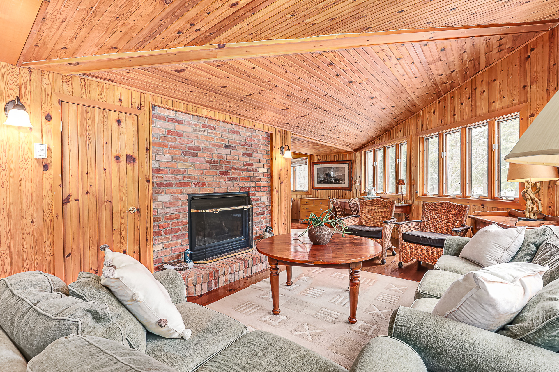A green velvet couch faces a brick wall with a black fireplace