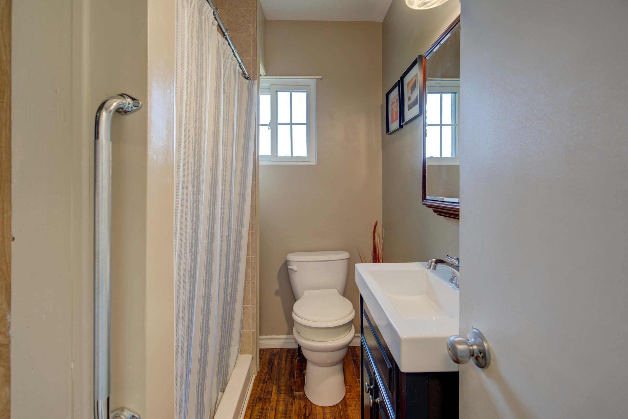 A narrow bathroom with a shower on the left and vanity on the right