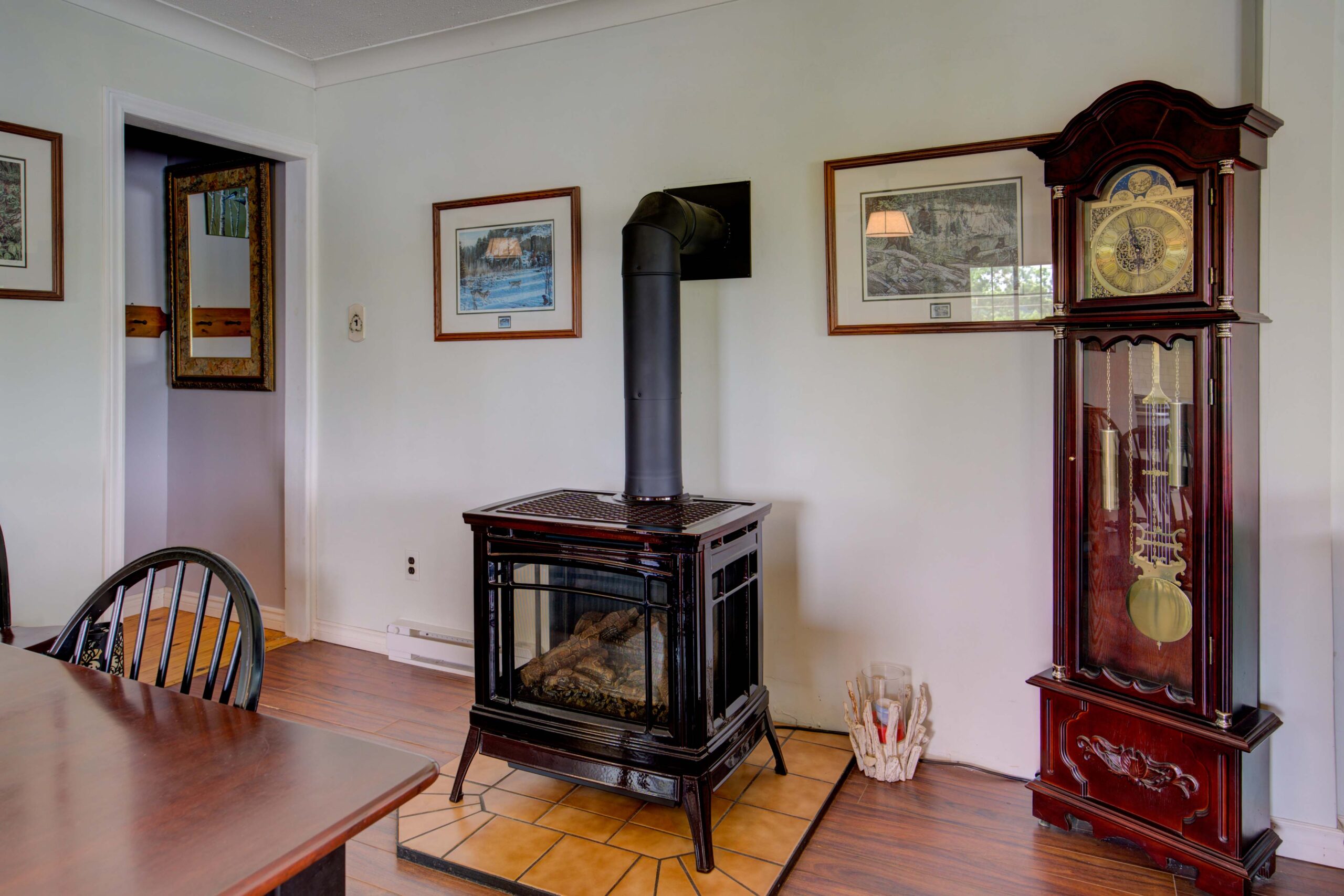 A black wood stove on a small wood platform in a white living room