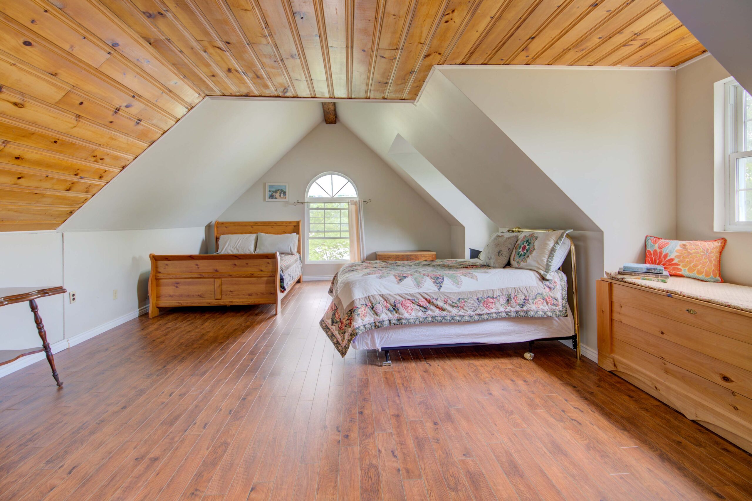 A quilted bed on the right faces a forward-facing bed in an attic room