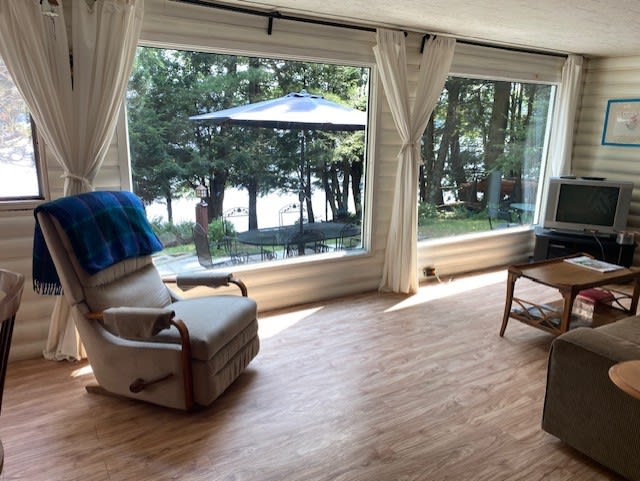 A beige chair next to bright lake-facing windows