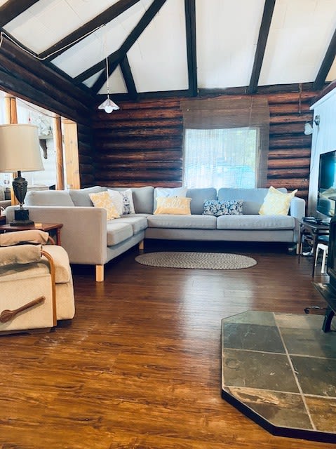 A grey L-shaped couch in a log room with vaulted ceilings