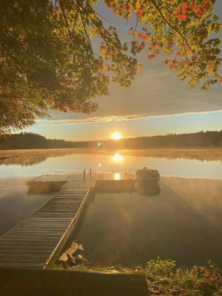 A dock on the lake with a sunset in the distance