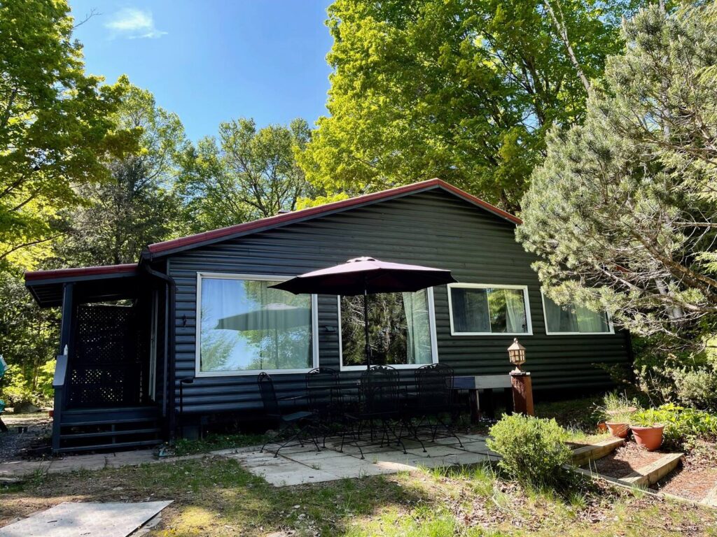 A black wood-paneled cottage with large windows