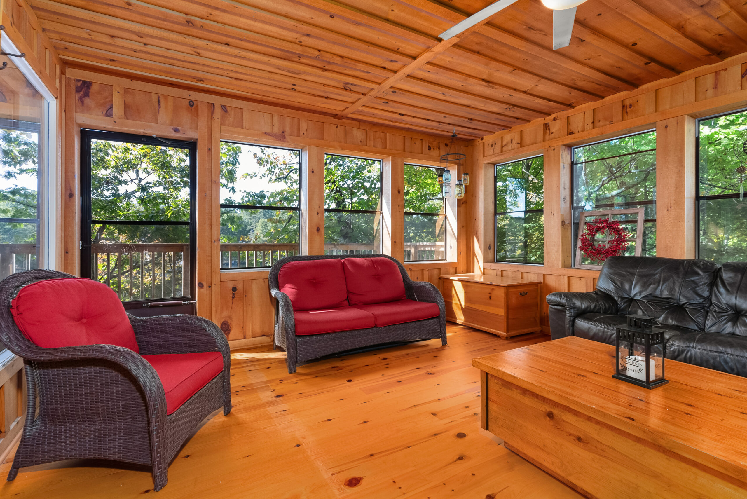 Enclosed sunroom with wicker seating and panoramic screened windows.