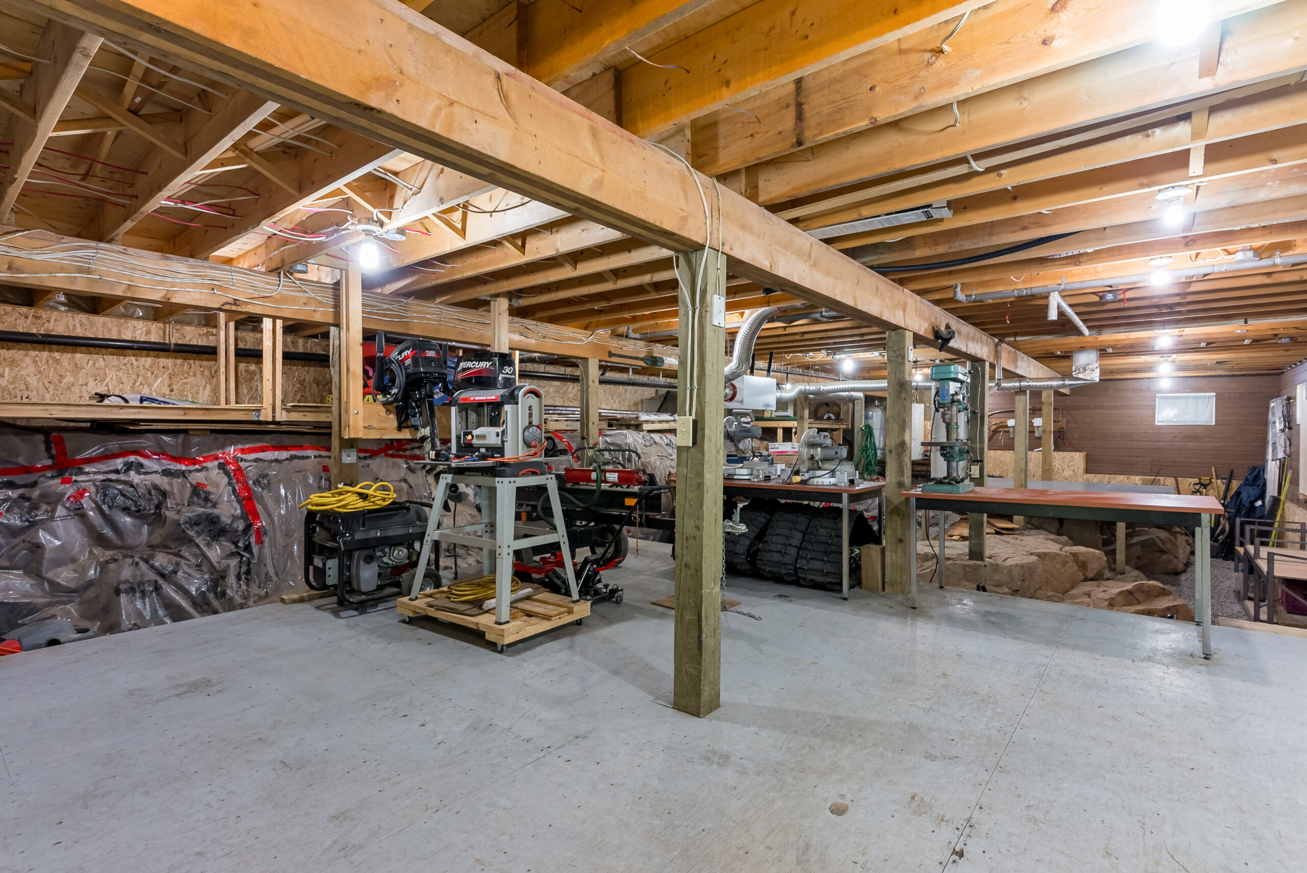 Spacious workshop with exposed beams and room for tools and recreational gear.