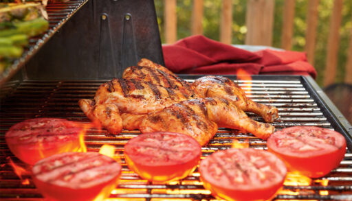 Spatchcocked chicken and tomatoes grilling on a barbecue