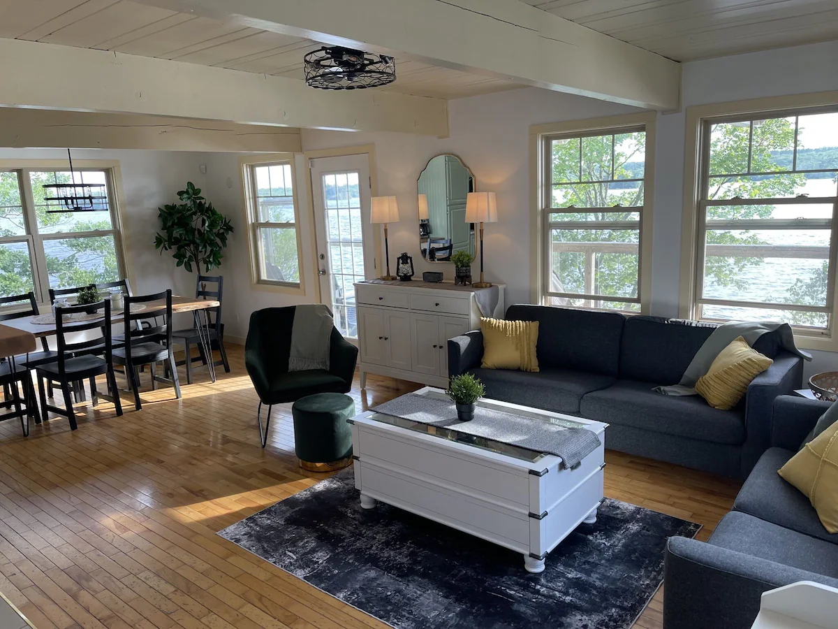 Grey couches face a white coffee table in a white living room with bright windows
