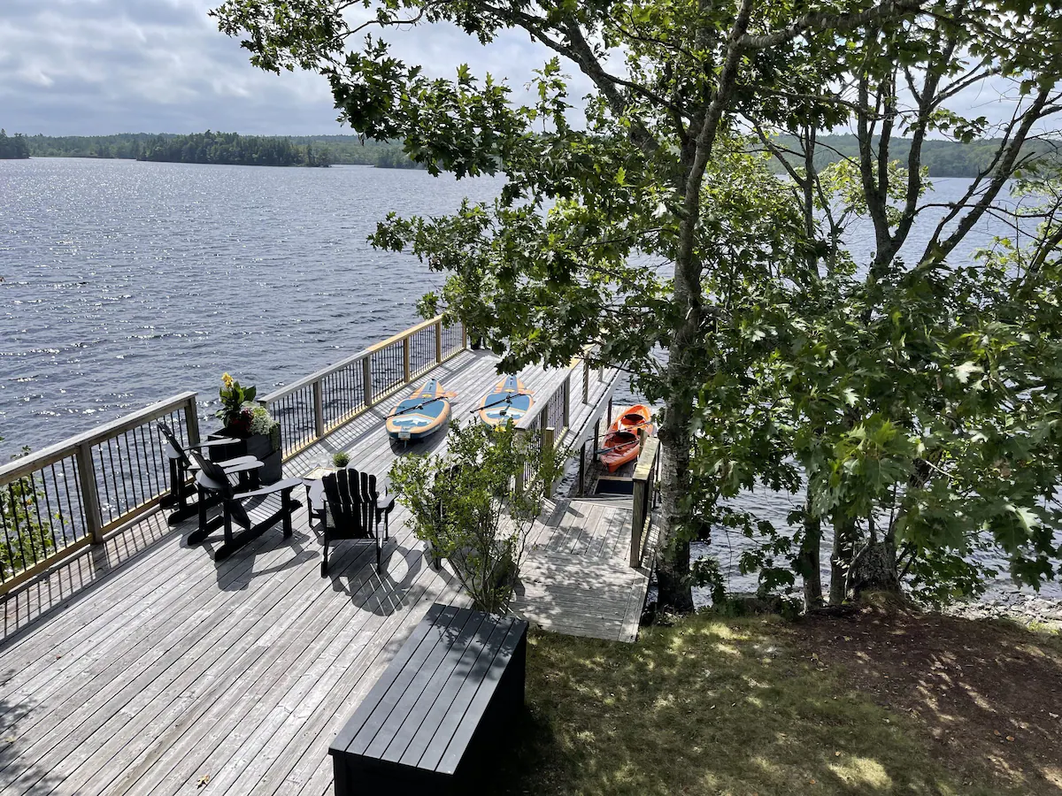 Aerial view of a wood terrace by the lake with black Muskoka chairs