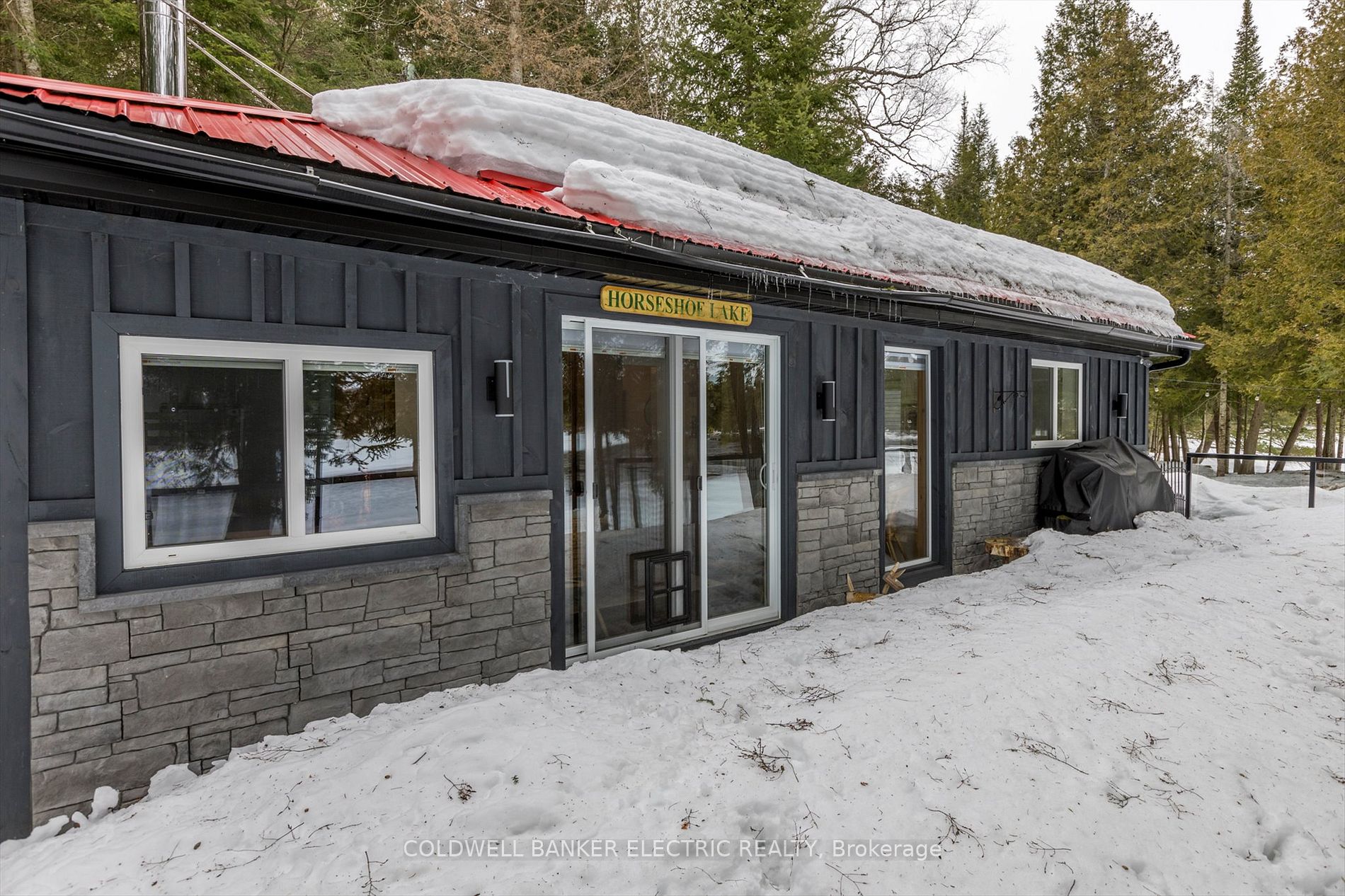 Snowy exterior with dark siding and metal roof