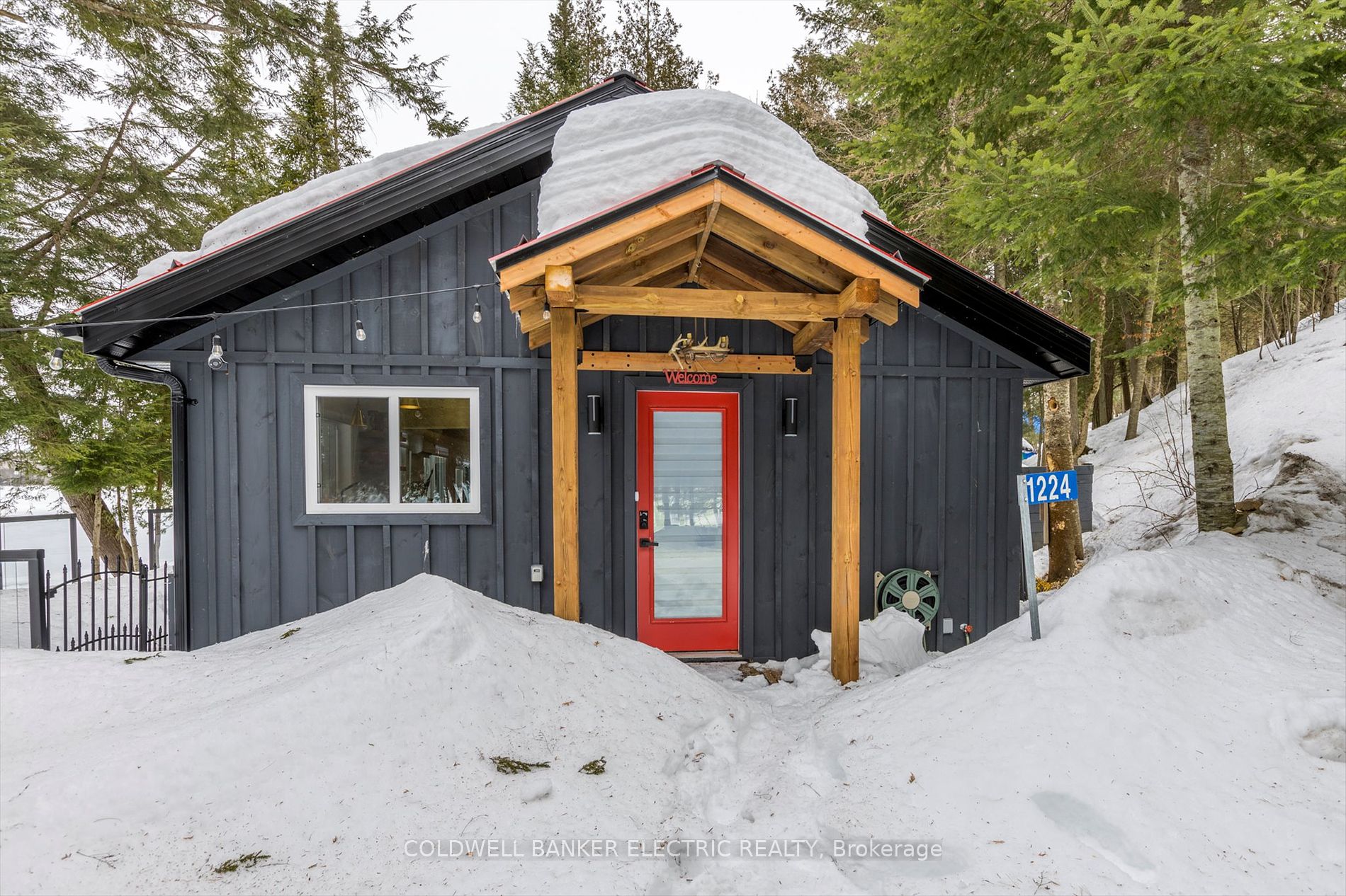 Red front door and covered entry with wood siding