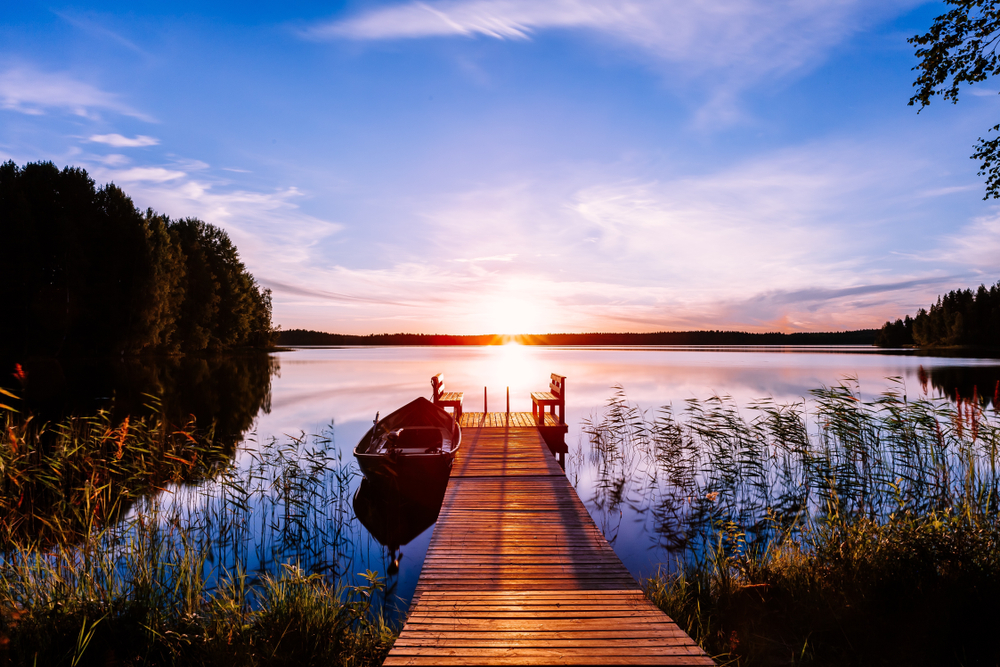 A dock and boat on a lake at sunset