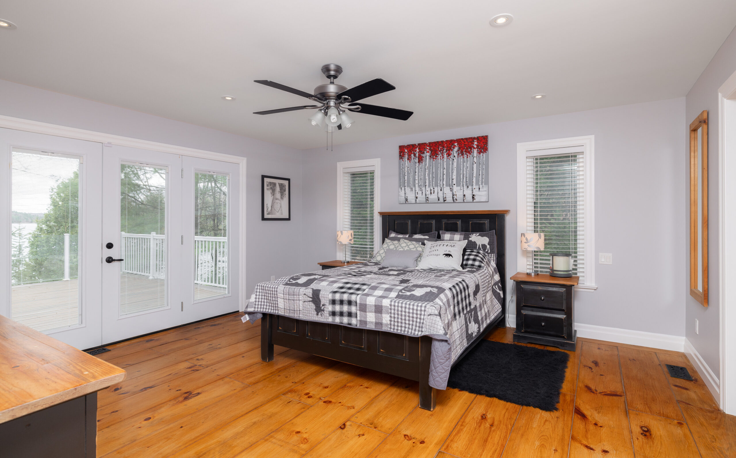 Bed in a bedroom with grey walls and hardwood floors.