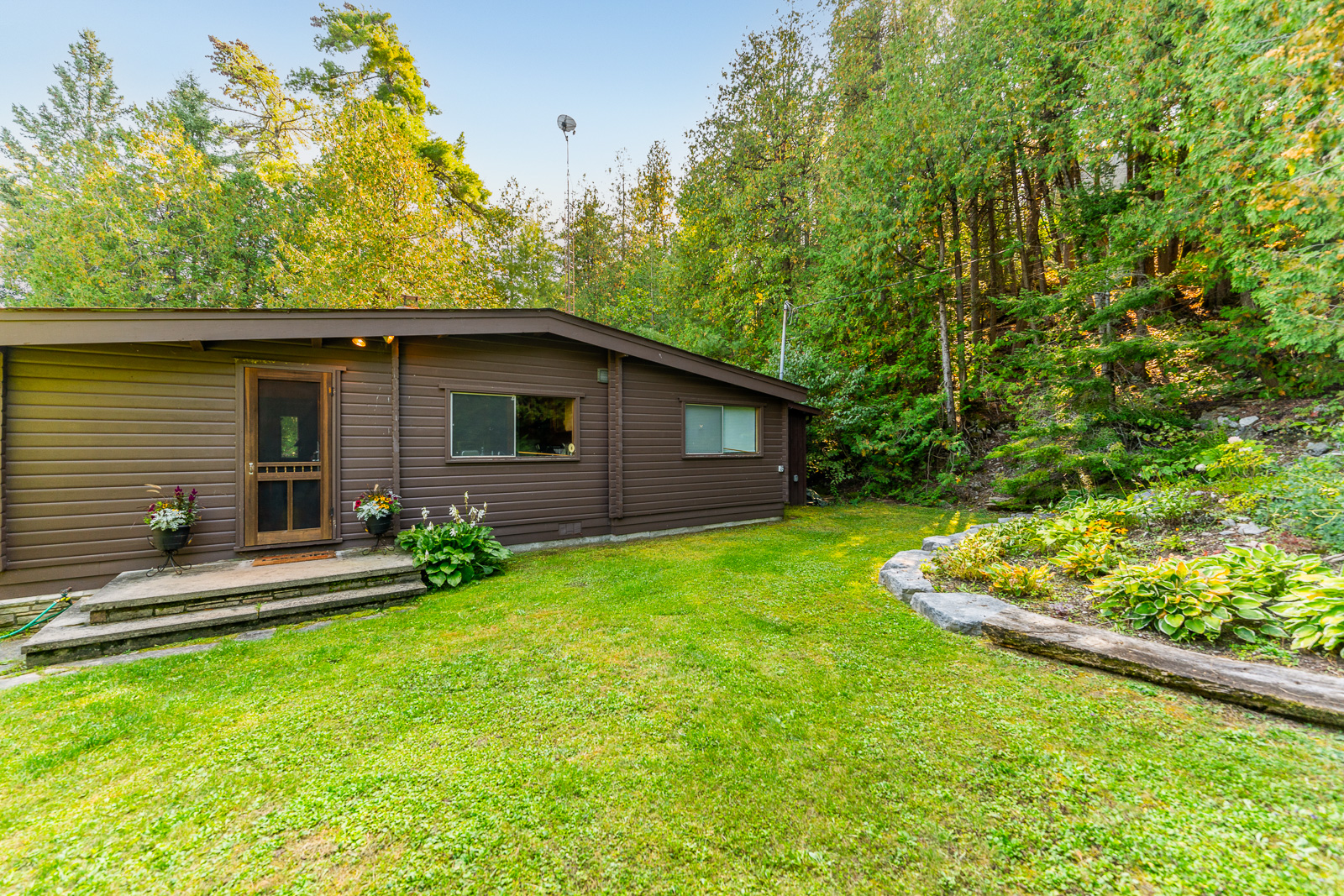 A dark brown paneled cottage on a grassy property