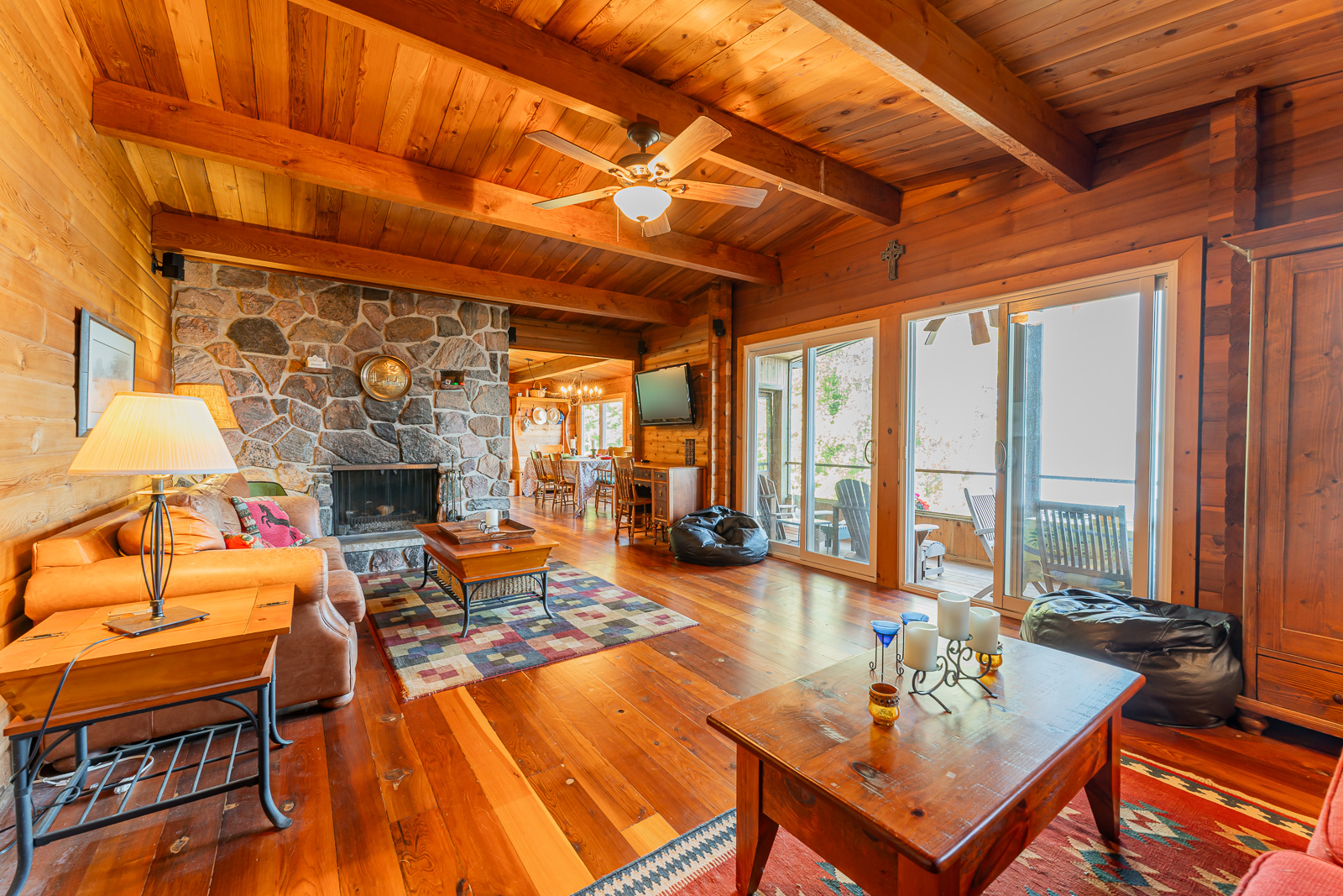 A wood living room with a stone fireplace and lake-faacing windows