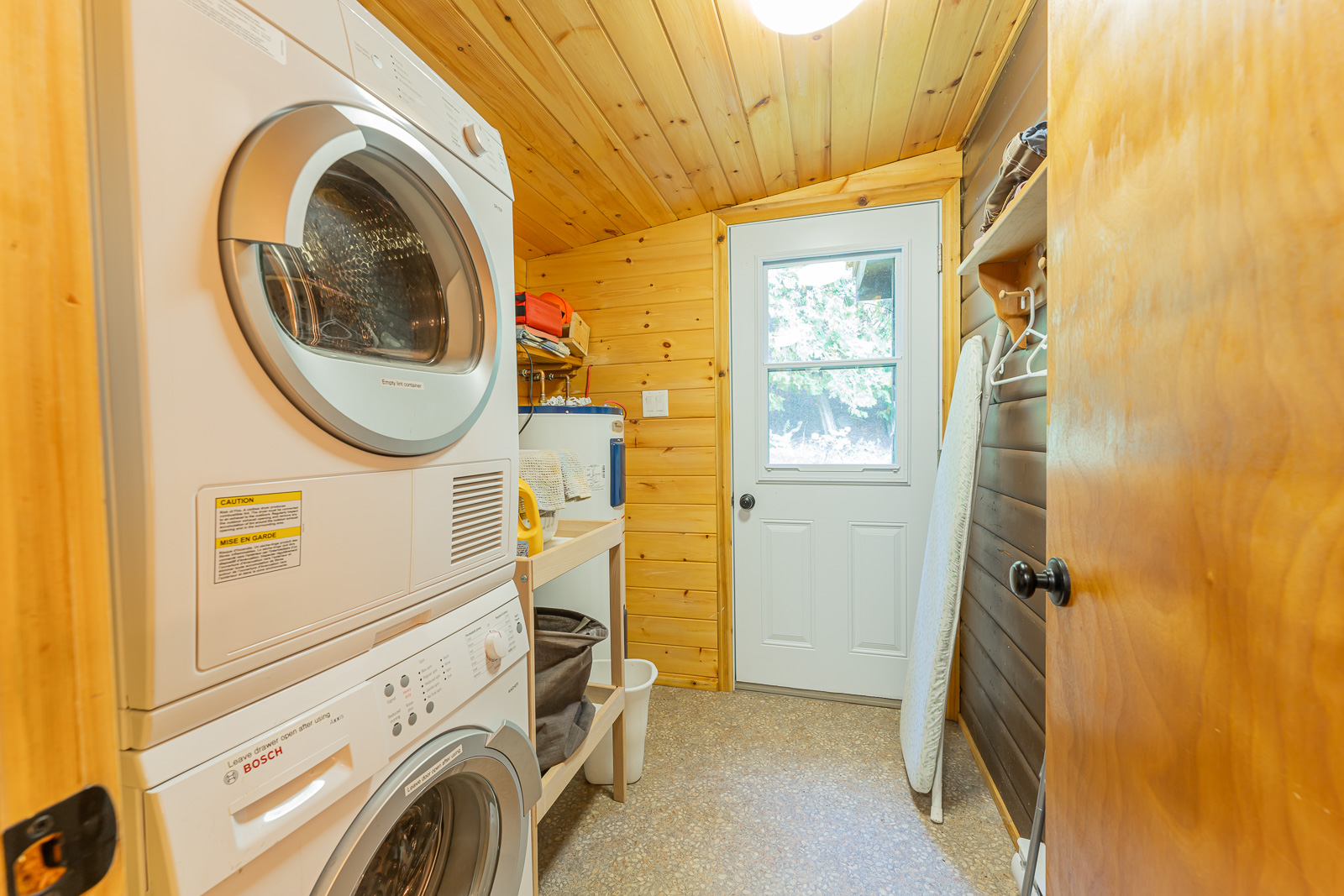 Stacked white laundry machines in a wood room