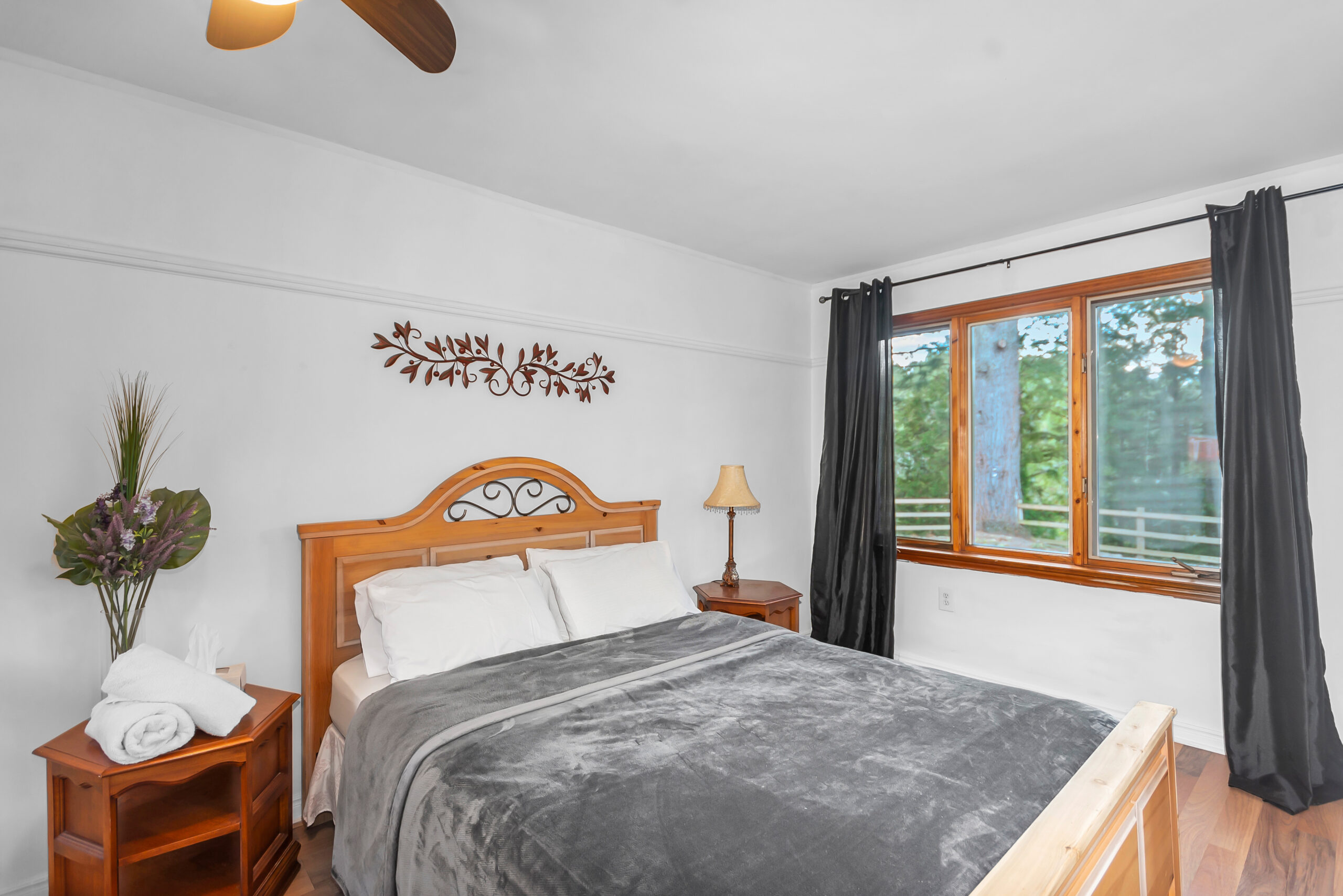 A wood bed with a grey cover in a white room