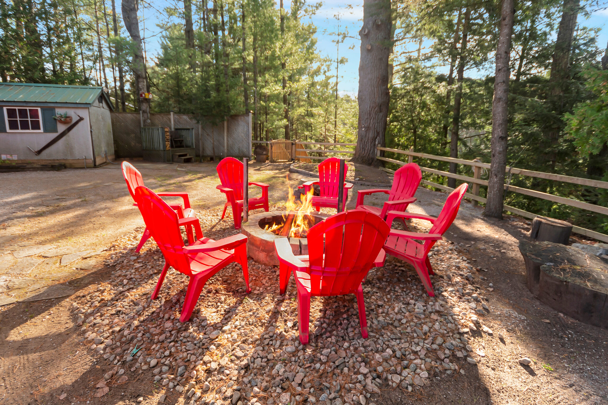A fire pit with red Muskoka chairs surrounding it
