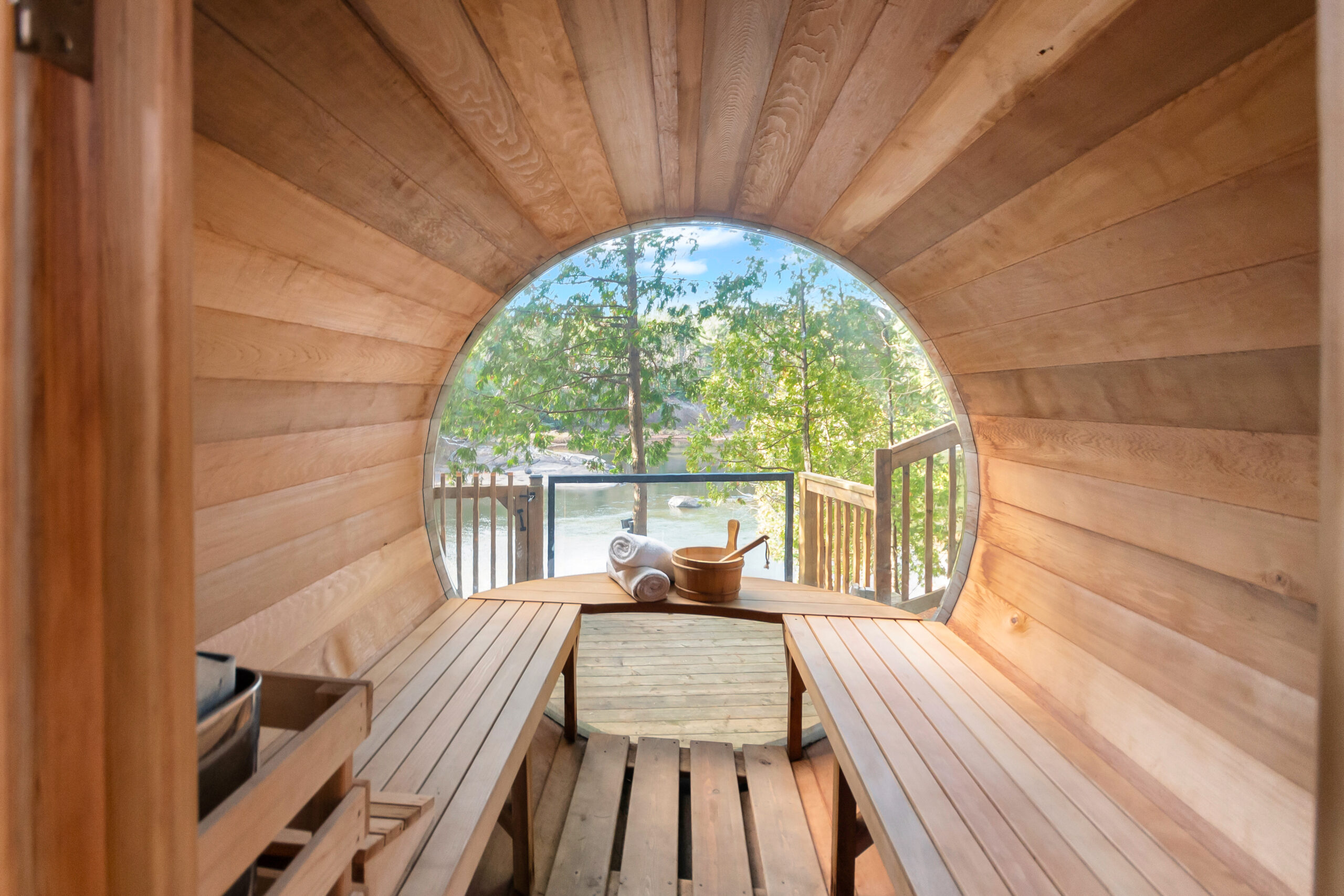 The interior of a barrel sauna looks out onto the lake