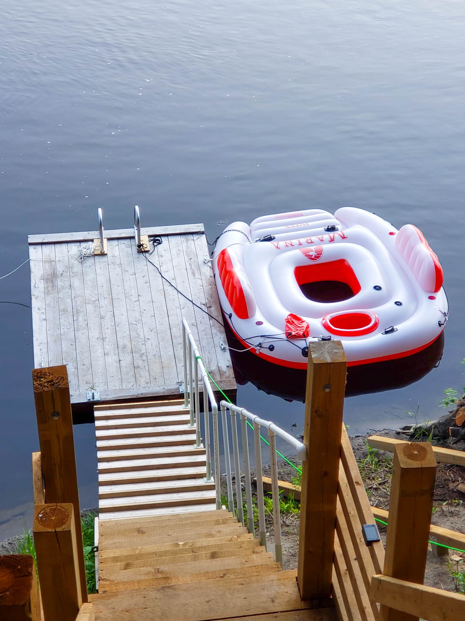 Wood steps lead down to the wood dock. Beside the dock, a donut-shaped inflatable