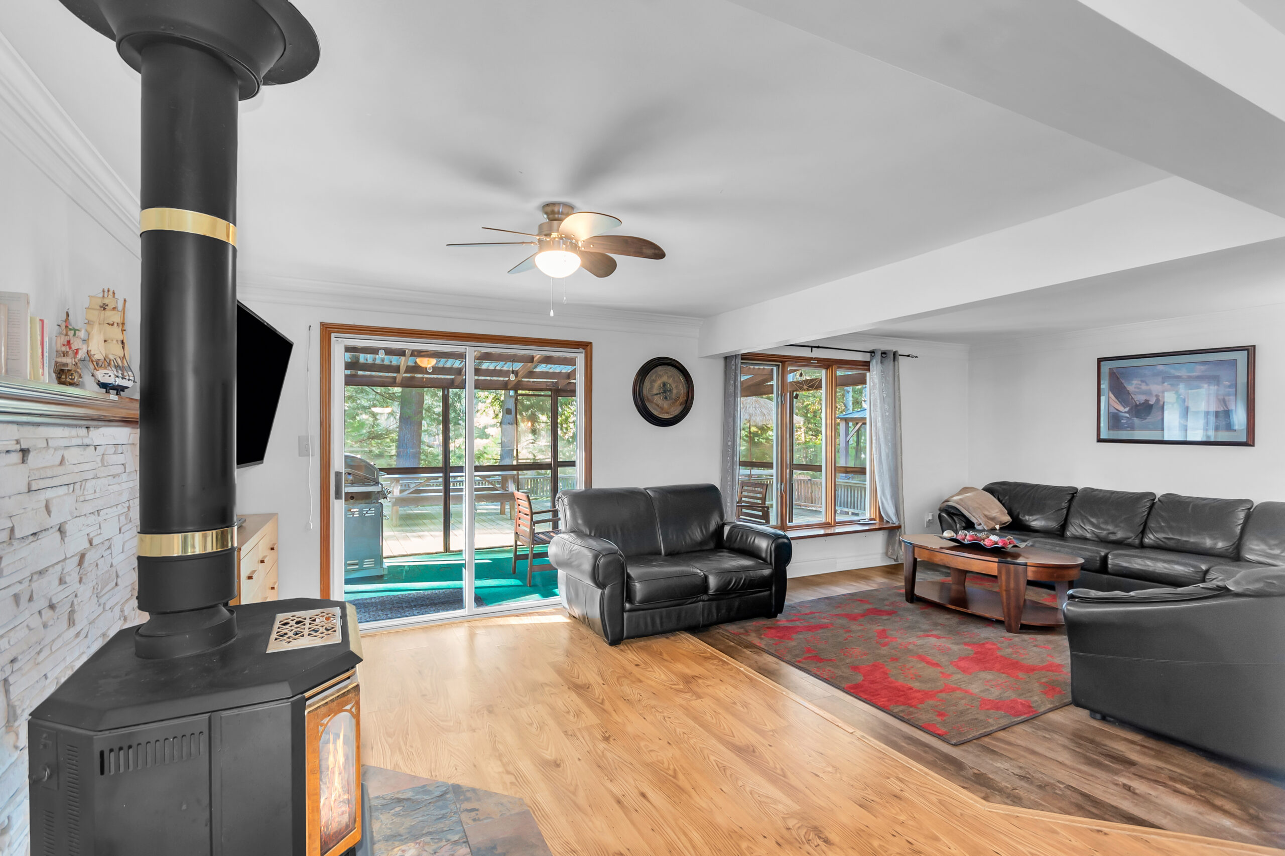 A spacious living room with black leather couches facing bright windows