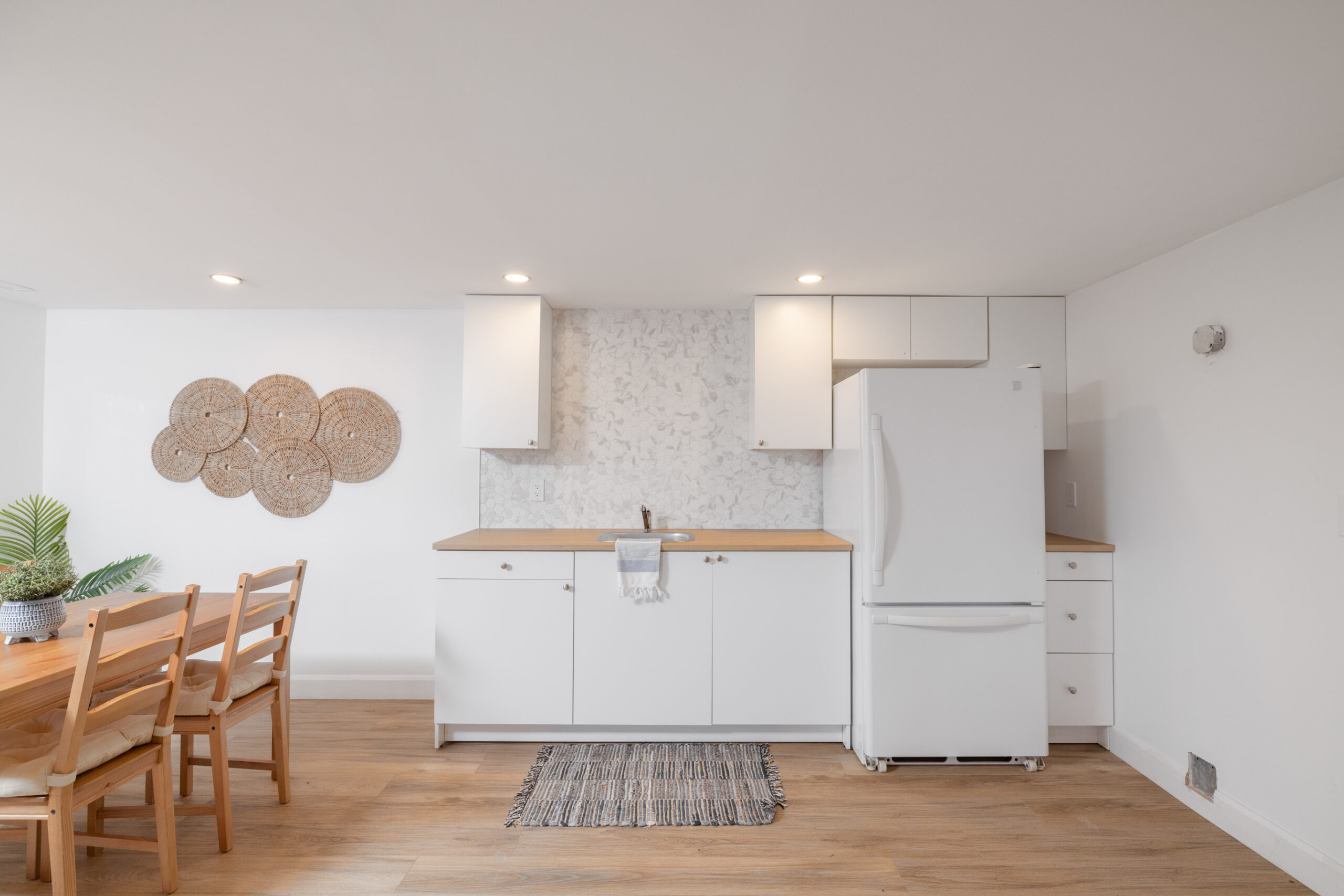 A small white kitchen with a white fridge