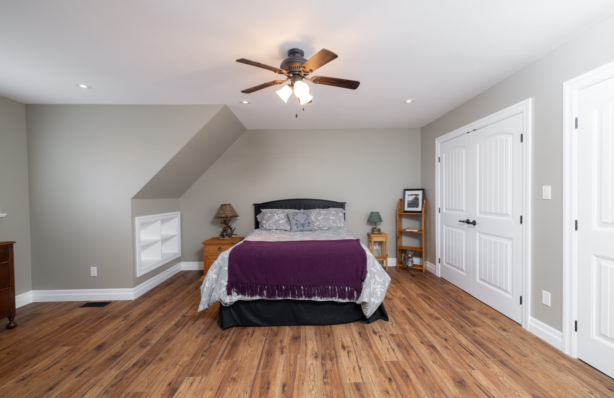 Bed in a bedroom with a closet and hardwood floors.