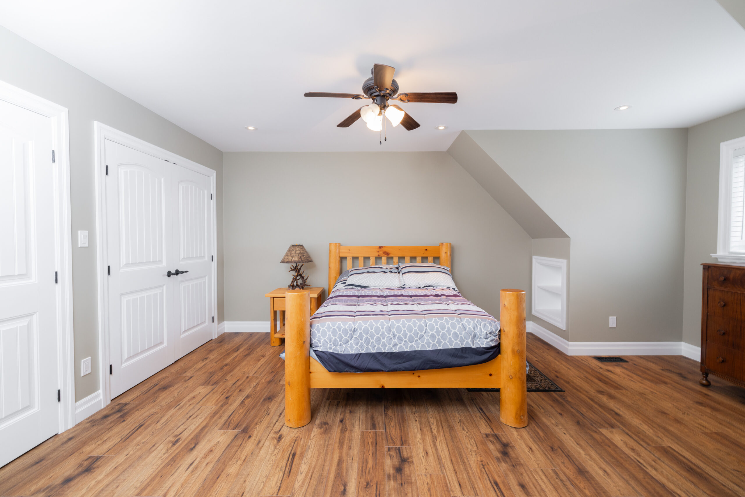 Room with a hardwood floors, a wooden bed, and a closet.
