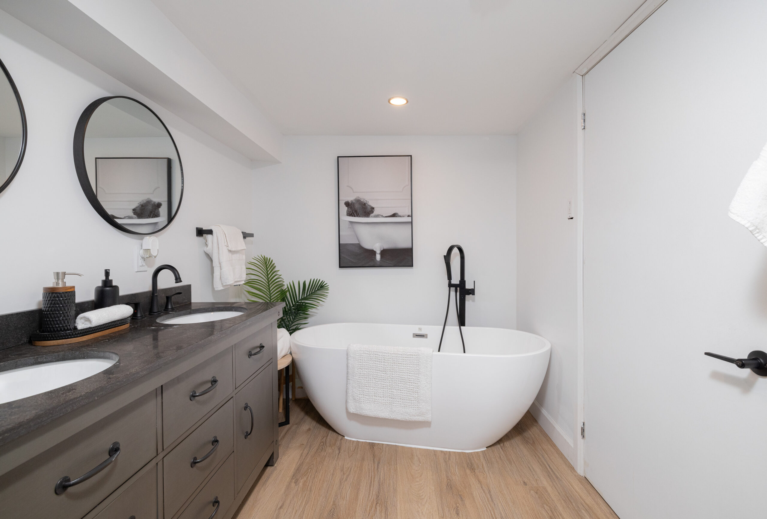 A freestanding tub next to a dark grey bathroom vanity
