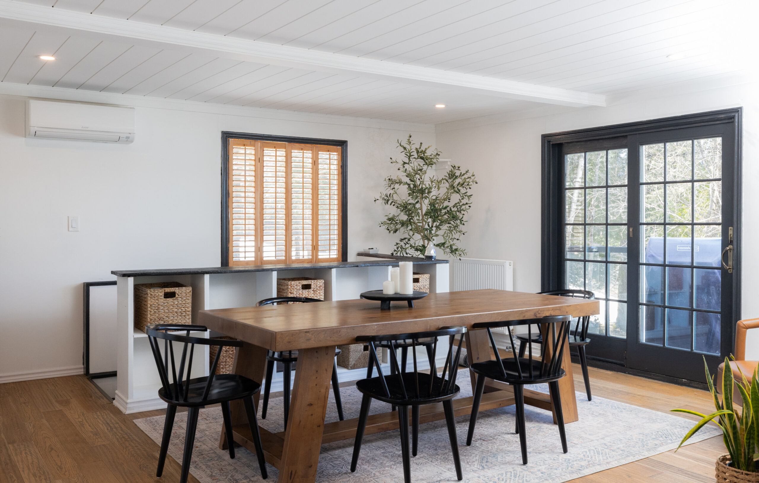 A long wood dining table with wood chairs in a white room