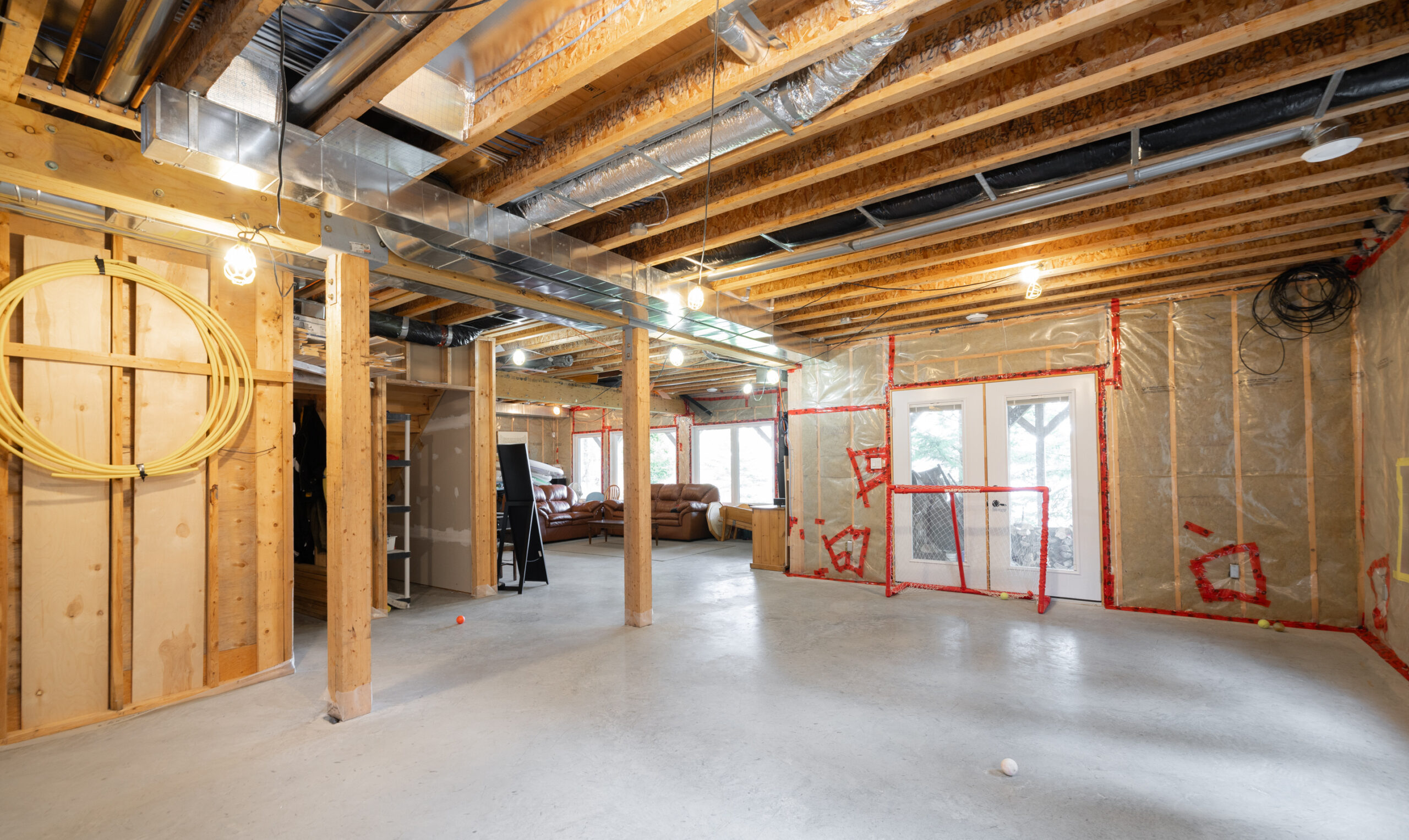 Unfinished basement with large windows, an exterior door, and a hockey net.