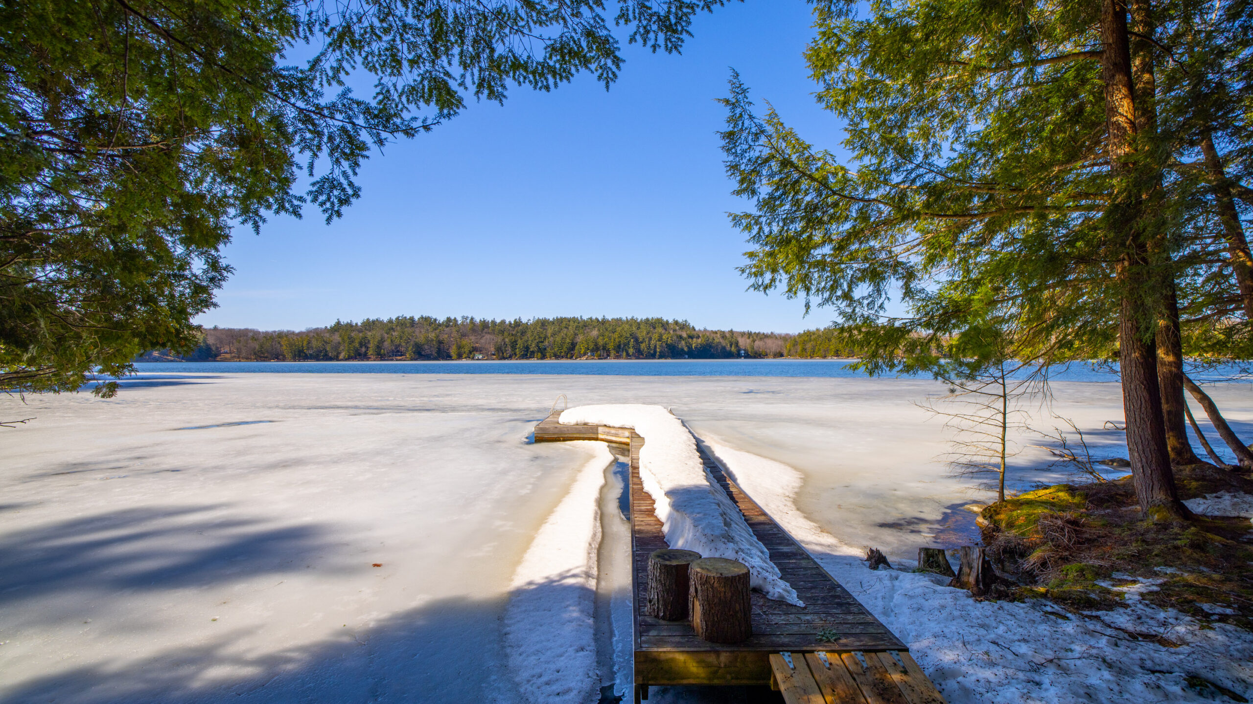 A long dock covered in snow leads out to the frozen lake