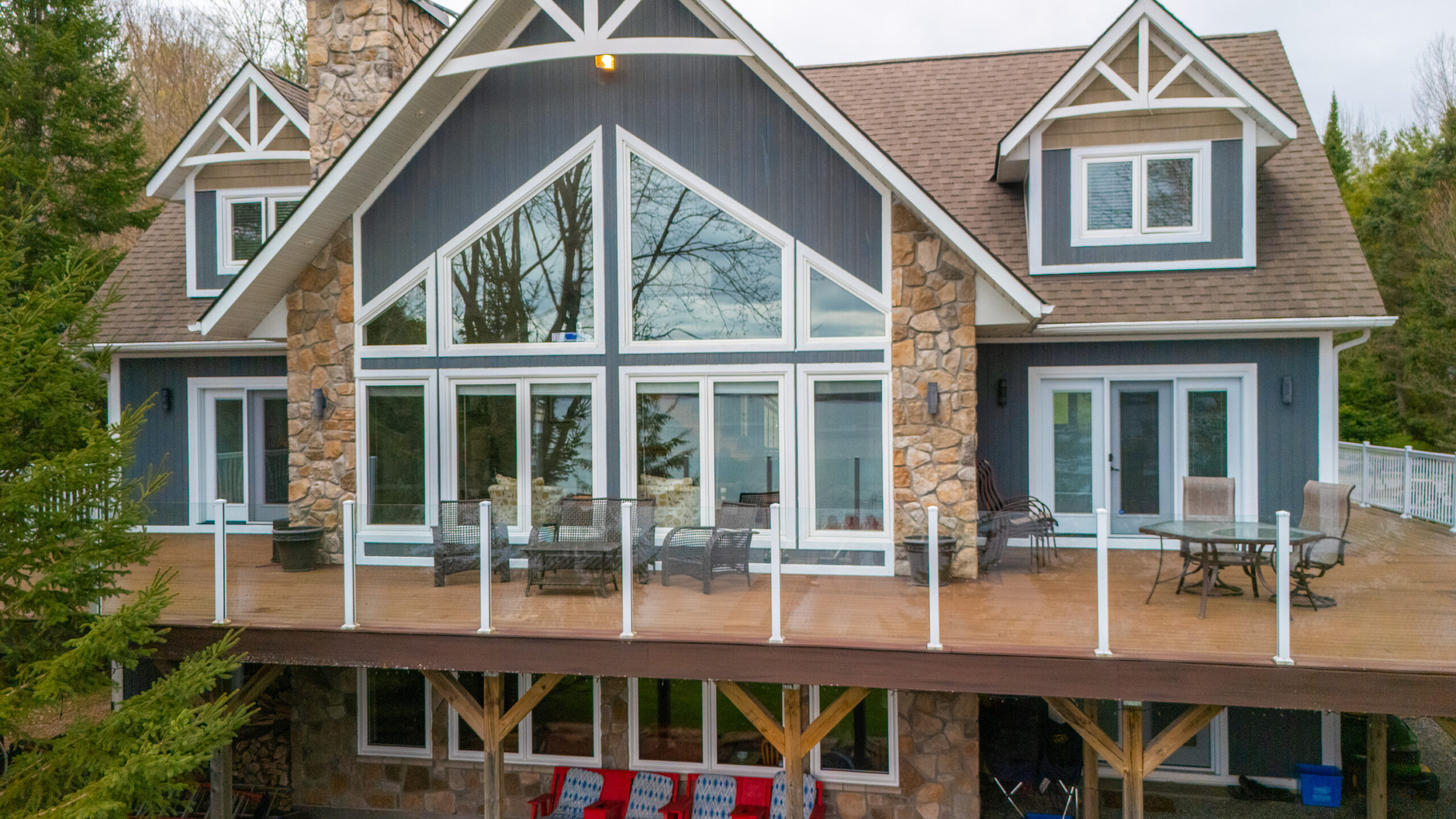Wraparound deck on a cottage with large windows.