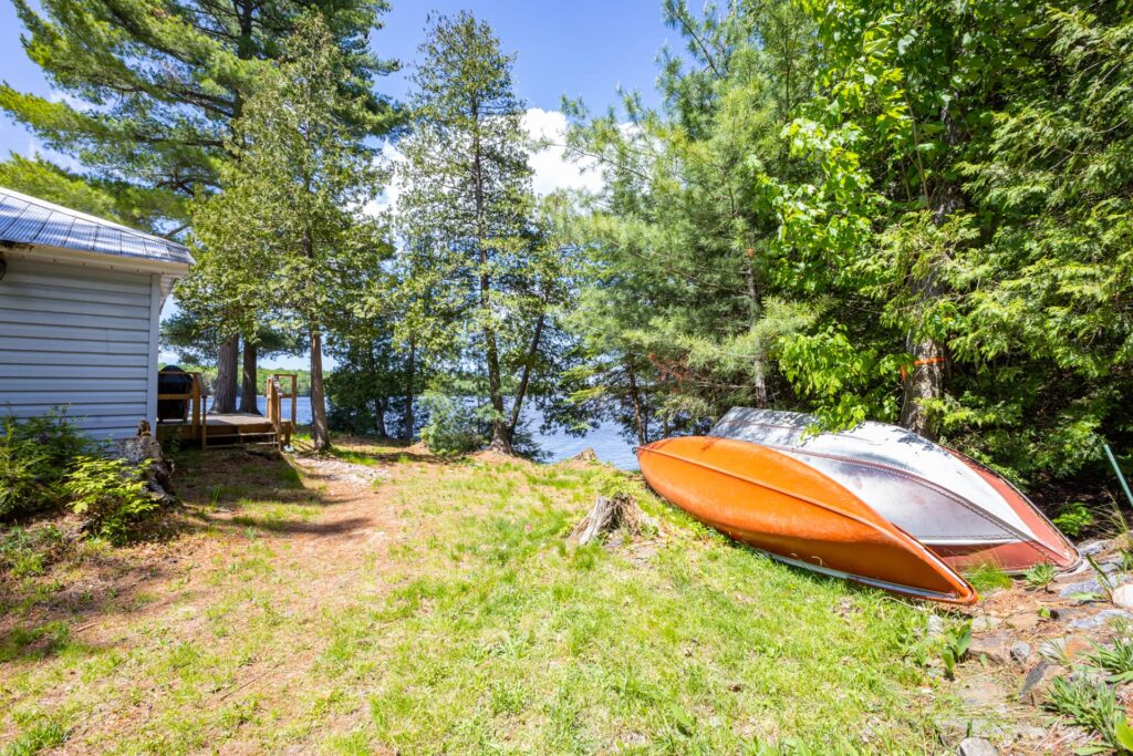 Orange canoe and aluminum rowboat resting on grass near Bear Lake shoreline