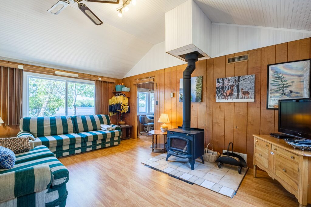 Living room with wood stove, striped couches, and large window facing the lake