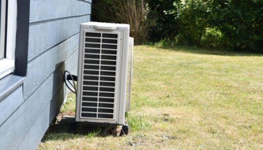 A heat pump device that heats a building (or part of a building) by transferring thermal energy from the outside using the refrigeration cycle installed on a wooden house in summer day