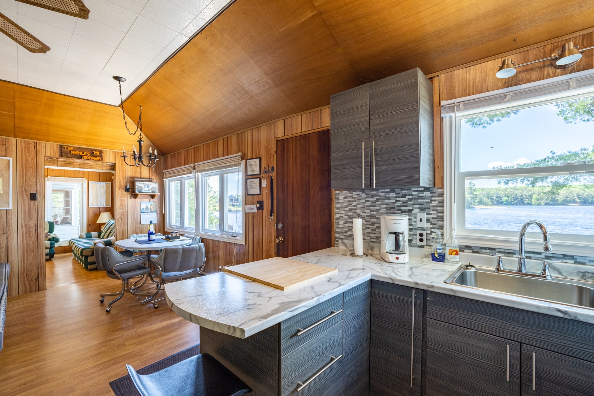 Open-concept kitchen and dining space with wood-paneled walls and lake view
