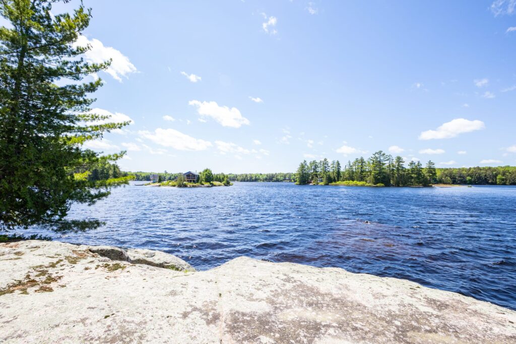 Scenic lake view from rocky shoreline with tree-lined islands in the distance