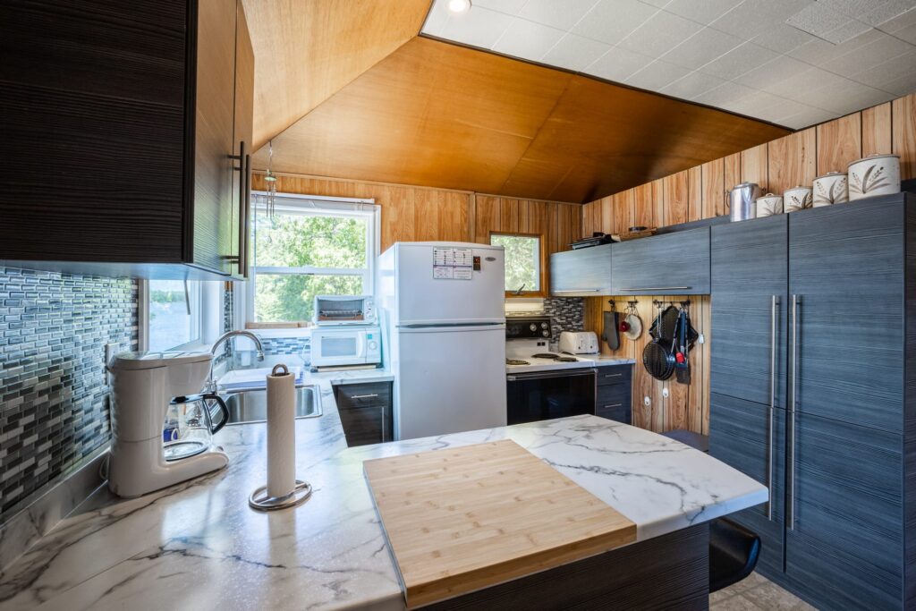 Fully equipped kitchen with marble counters, wood ceiling, and lake-view window