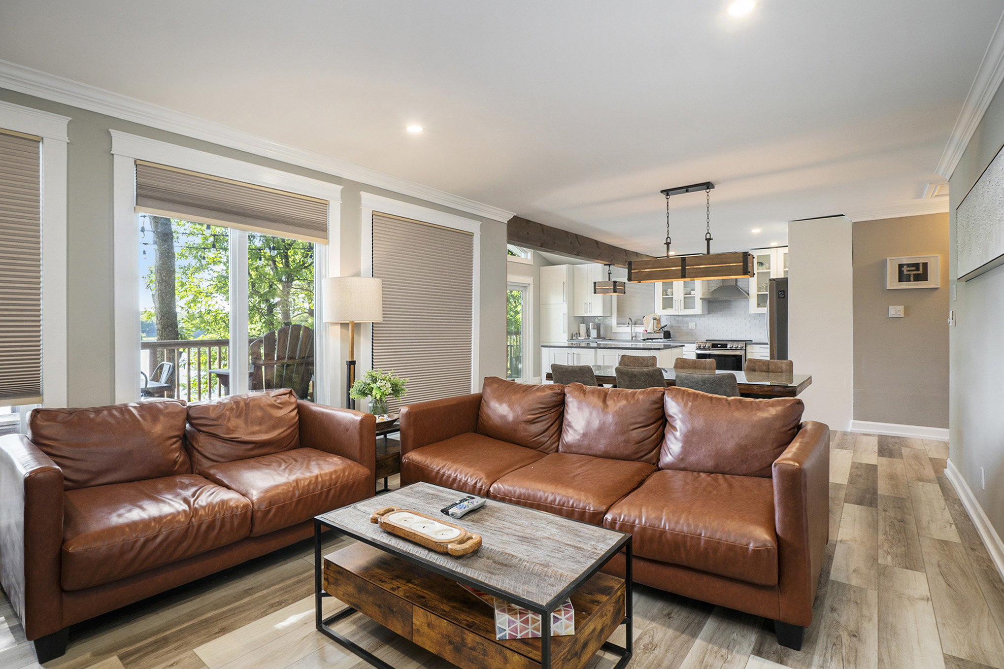 Bright and airy open-concept living and dining area with leather seating and views into the kitchen