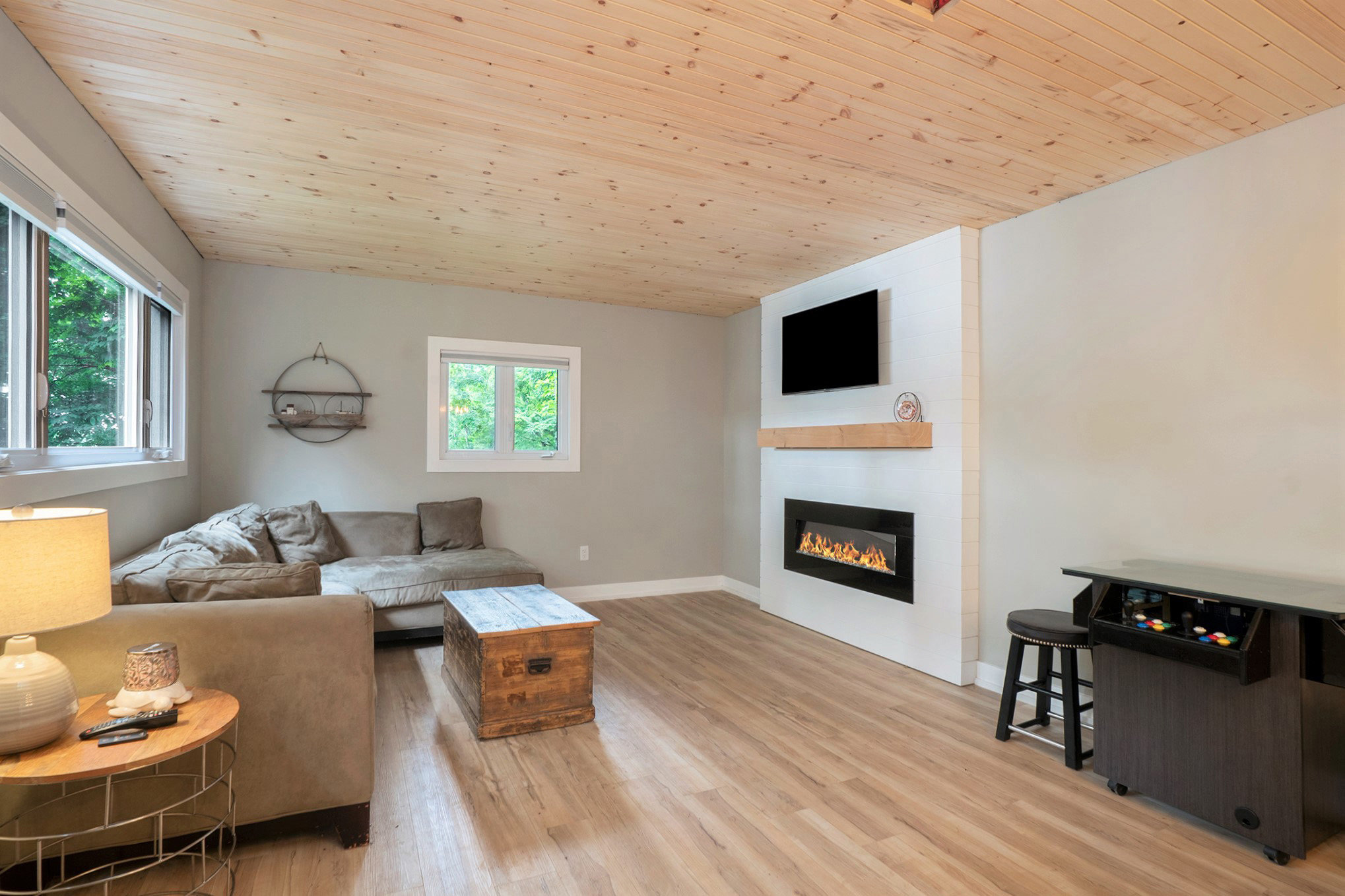 Cozy secondary sitting area with vaulted wood ceiling, natural light, and wall-mounted TV