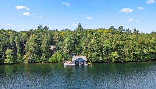 Wide-angle view of the island compound showing the shoreline and multiple buildings surrounded by trees