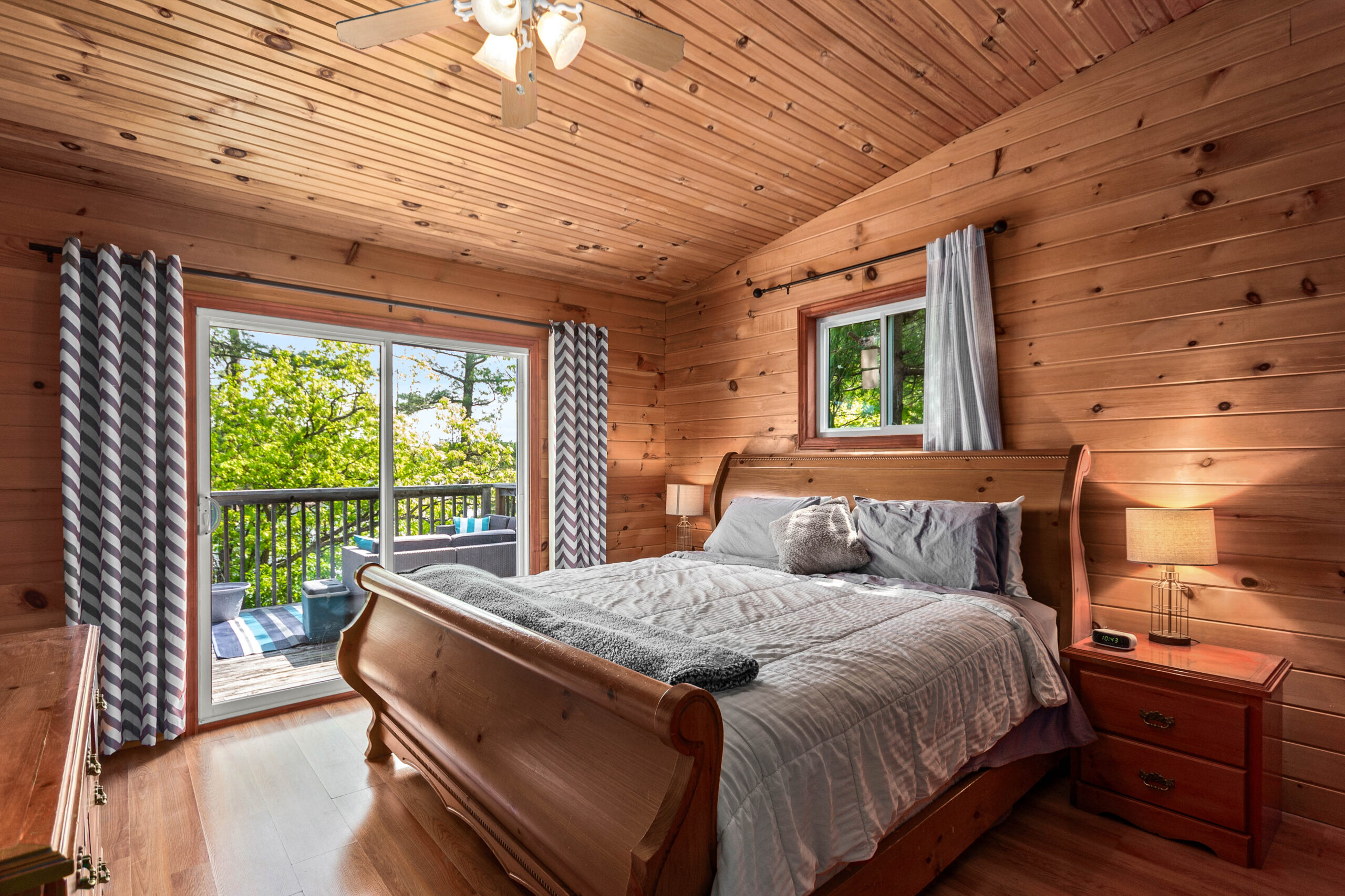 A wood bed with a grey bedspread in a wood-paneled room
