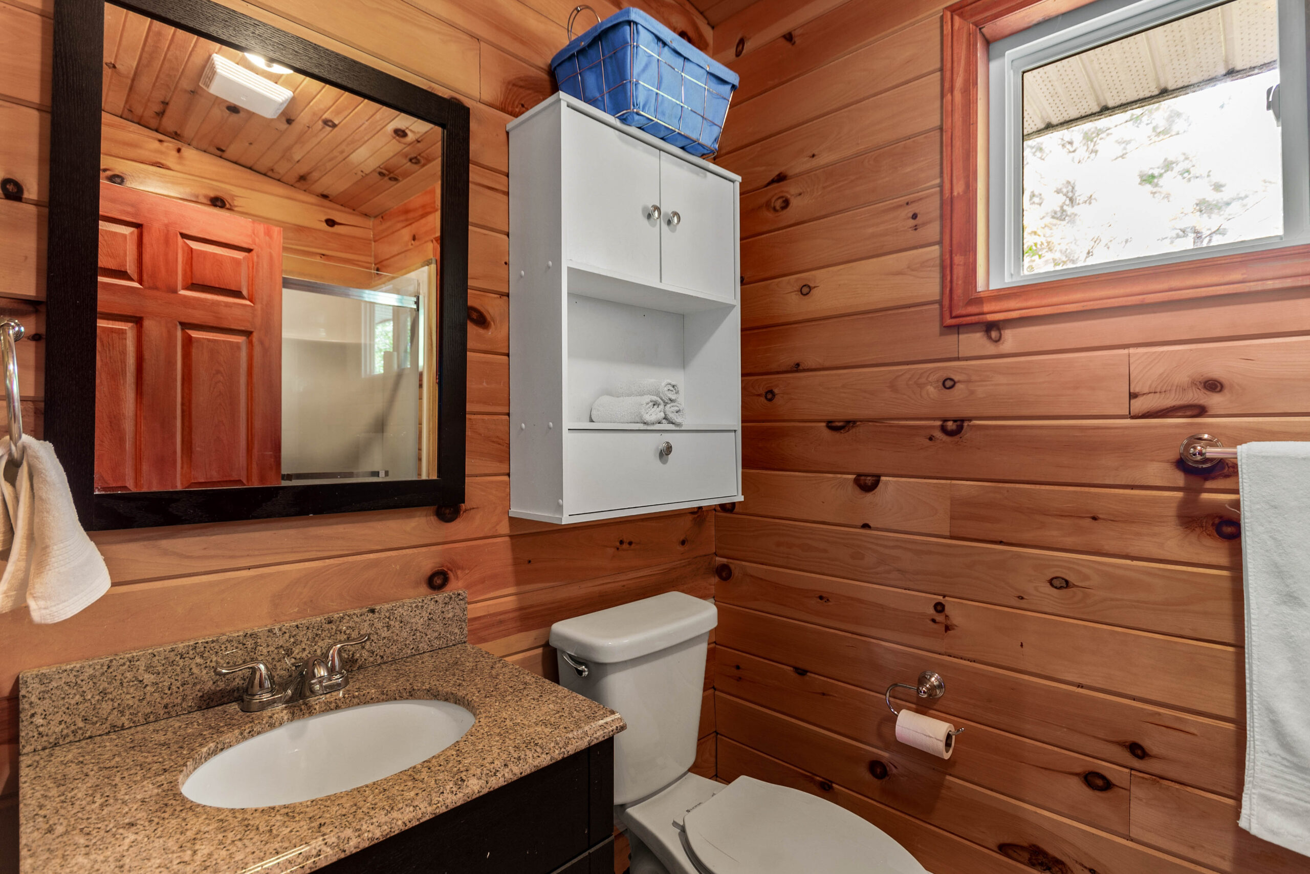 A beige marble vanity with a square mirror hanging above
