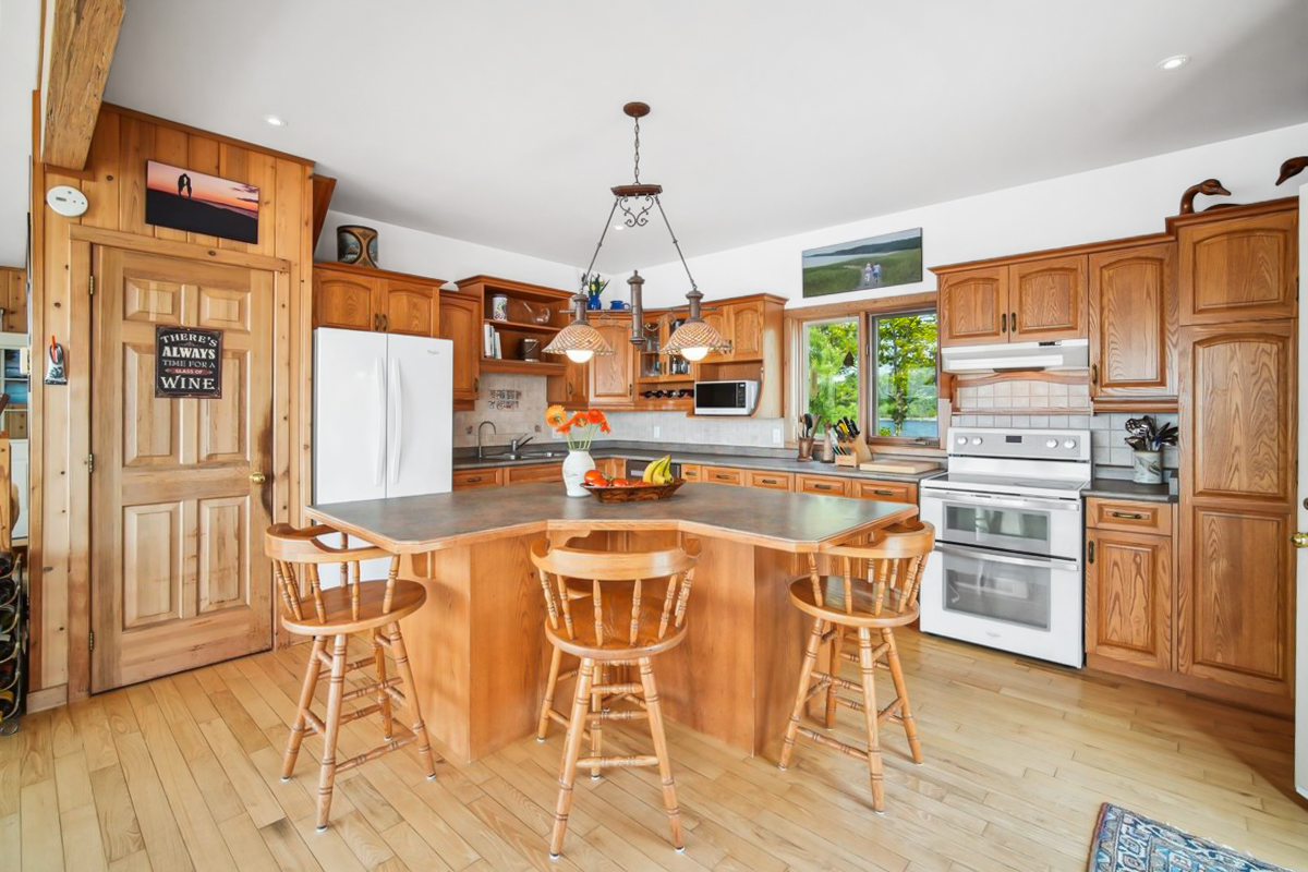 Bright kitchen with natural wood cabinetry, central island with bar stools, and stainless appliances