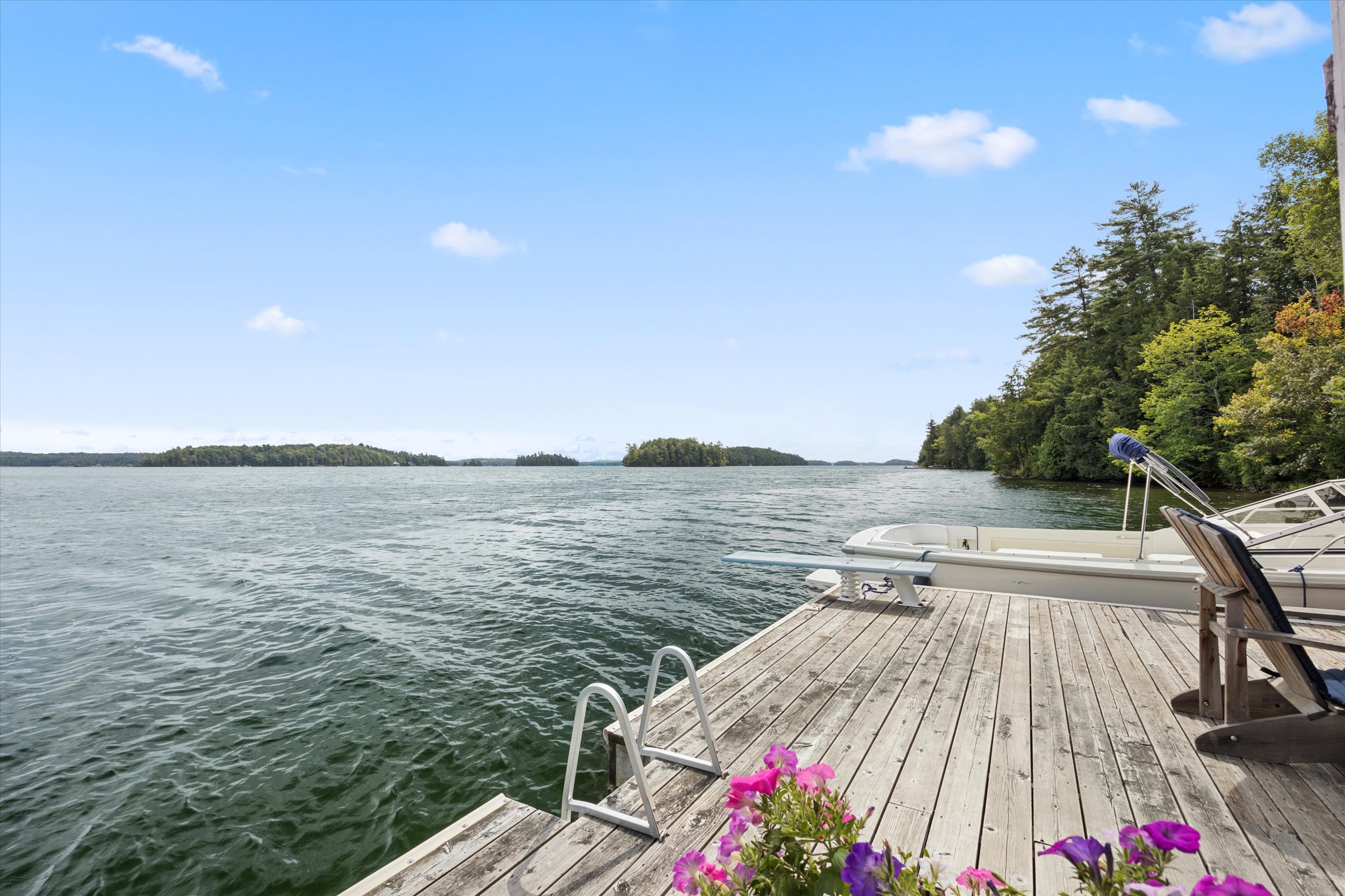 Peaceful view from a dock on Lake Joseph with blue skies, calm water, and distant shoreline