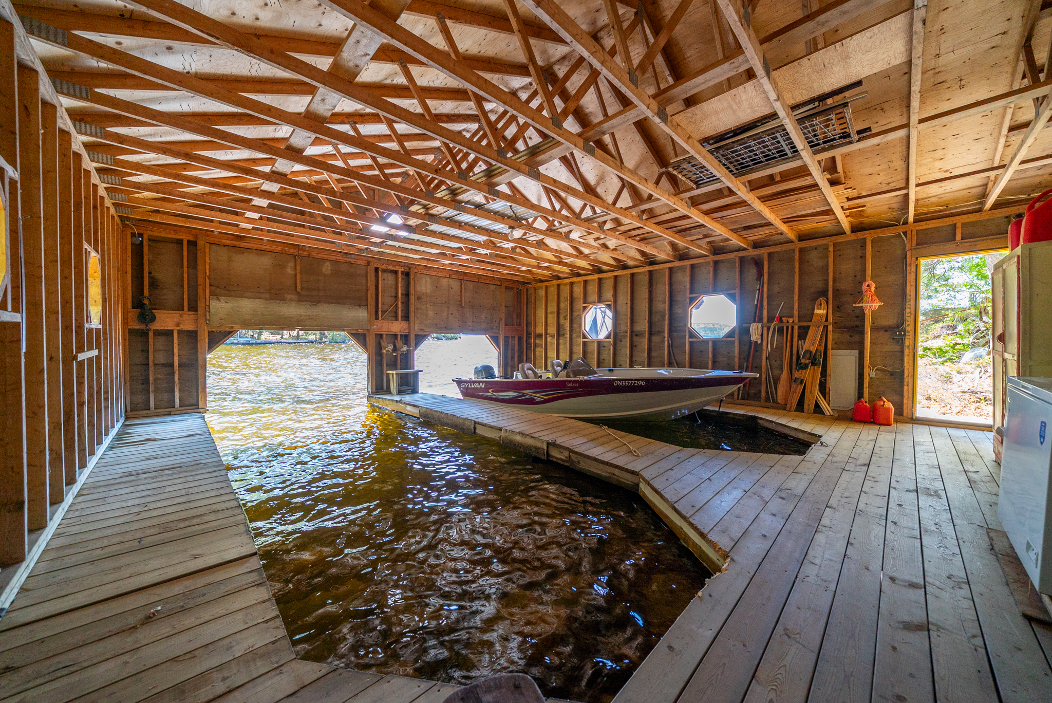 Inside view of wooden boathouse with two boat slips and open rafter ceiling