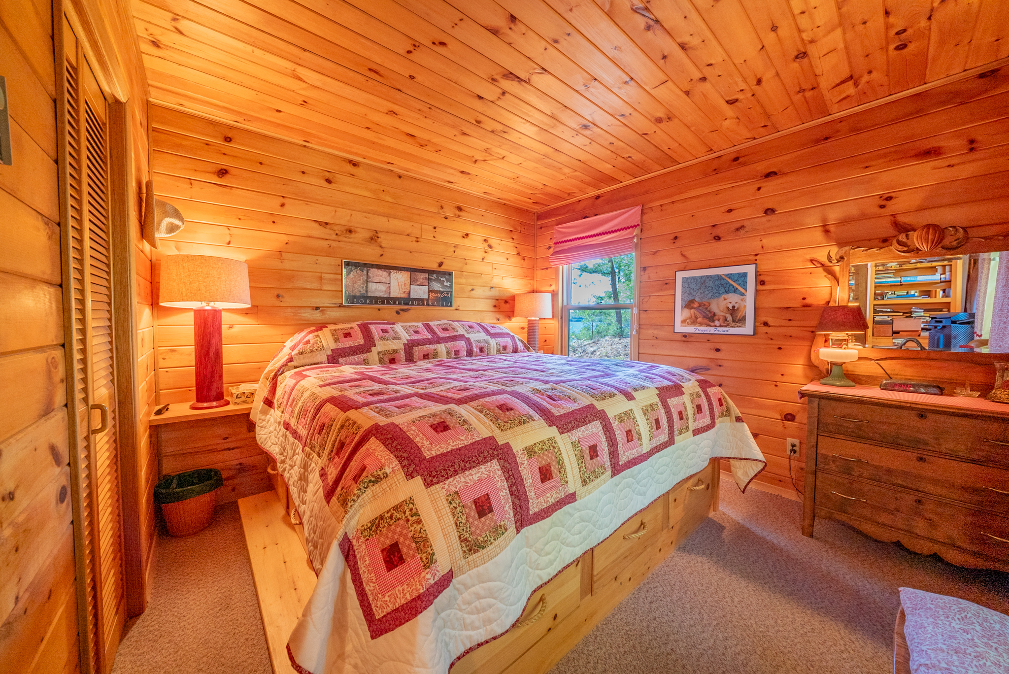 Cheerful bunk bedroom in separate bunkie with log-style beds and cottage-themed decor